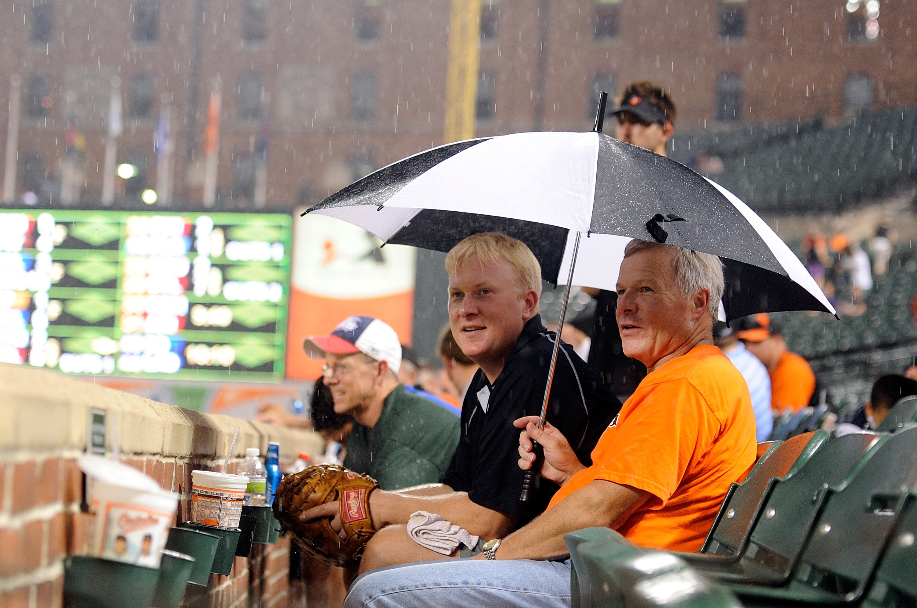 BALTIMORE - AUGUST 04:  Fans watch the grounds crew put the tarp on the field during a rain delay in the sixth inning of the game between the Los Angeles Angels of Anaheim and the Baltimore Orioles at Camden Yards on August 4, 2010 in Baltimore, Maryland.