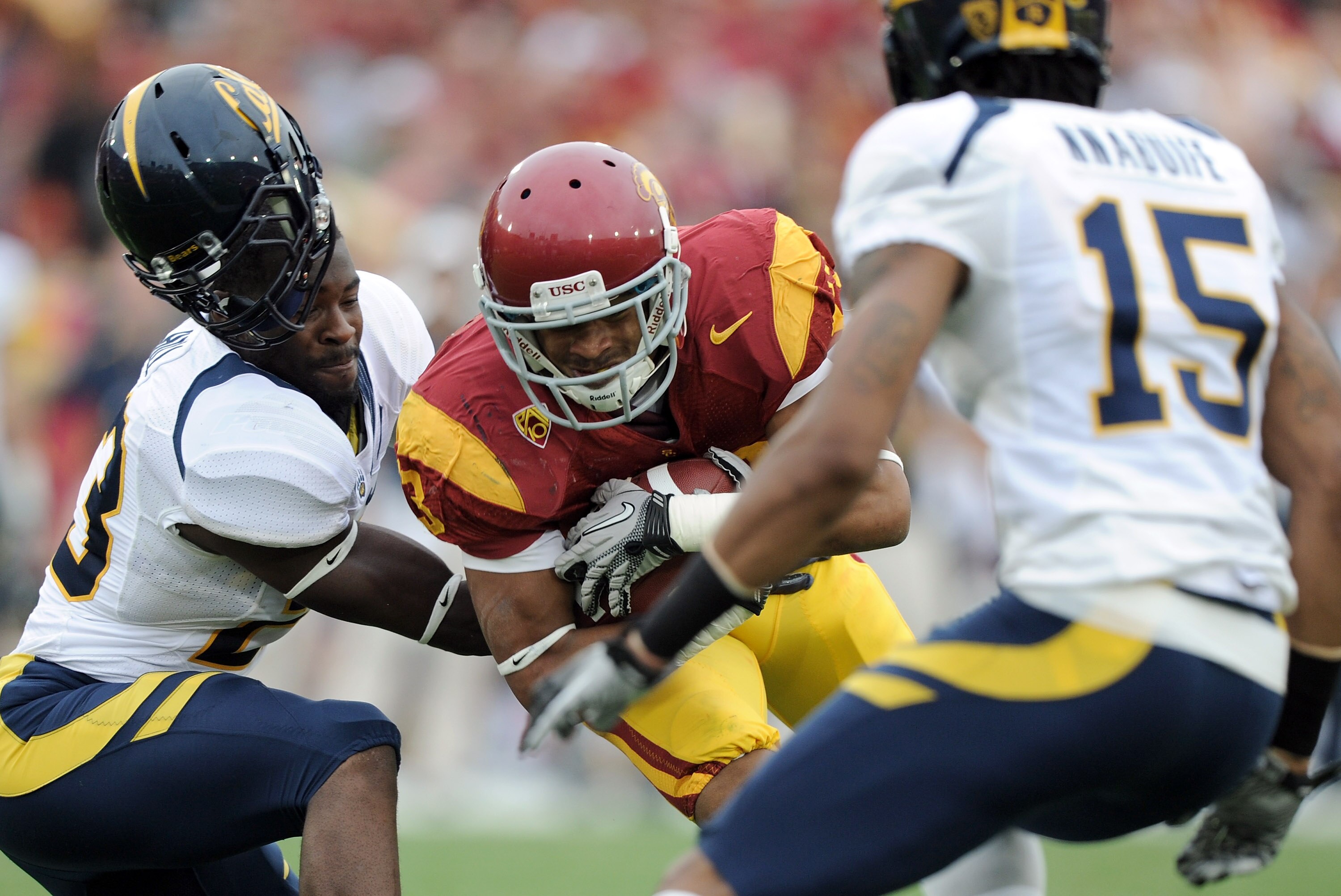 LOS ANGELES, CA - OCTOBER 16:  Robert Woods #13 of the USC Trojans is tackled by Josh Hill #23 and Bryant Nnabuife #15 of the California Golden Bears during the second quarter at Los Angeles Memorial Coliseum on October 16, 2010 in Los Angeles, California
