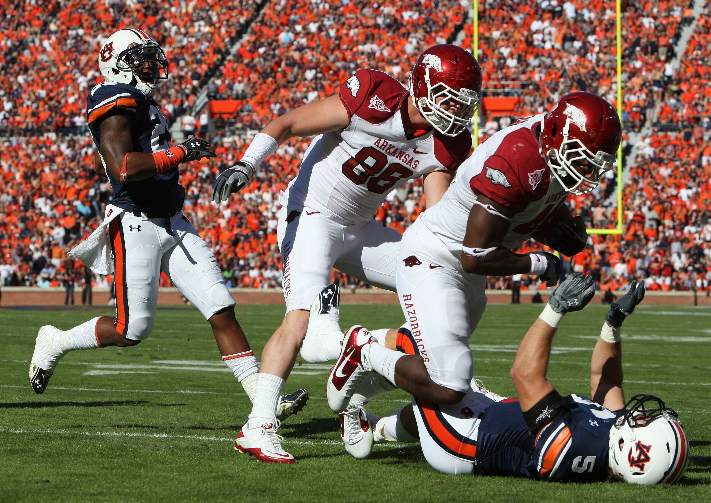 AUBURN - OCTOBER 16:  Fullback Van Stumon #44 of the Arkansas Razorbacks (second from right) runs over linebacker Jake Holland #5 of the Auburn Tigers (on the ground) while tight end Garrett Uekman #88 of the Arkansas Razorbacks (center) looks on during t