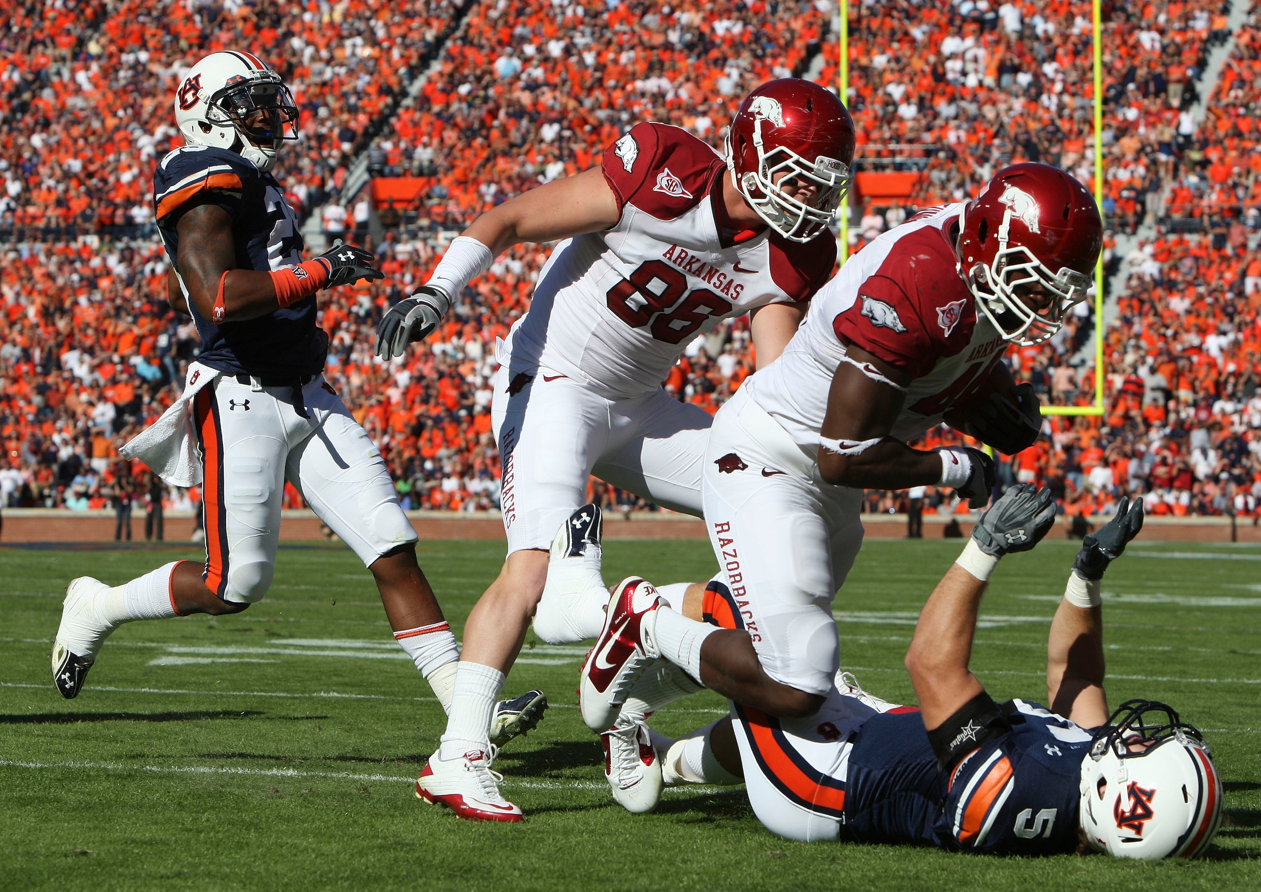 AUBURN - OCTOBER 16:  Fullback Van Stumon #44 of the Arkansas Razorbacks (second from right) runs over linebacker Jake Holland #5 of the Auburn Tigers (on the ground) while tight end Garrett Uekman #88 of the Arkansas Razorbacks (center) looks on during t