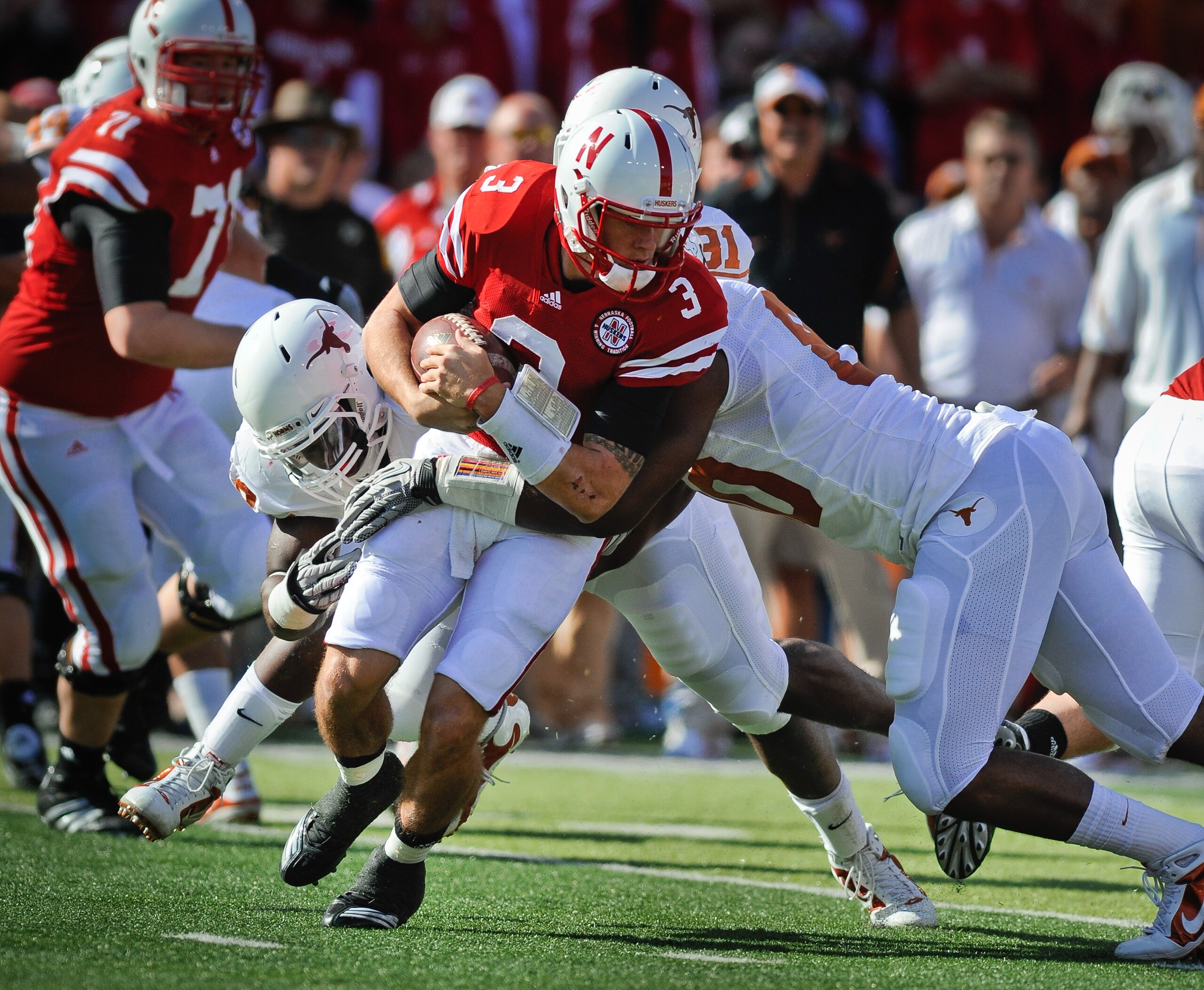 LINCOLN, NE - OCTOBER 16: Quarterback Taylor Martinez #3 of the Nebraska Cornhuskers tries to slip the grasp of defensive end Alex Okafor #80 and linebacker Emmanuel Acho #18 of the Texas Longhorns during first half action of their game at Memorial Stadiu
