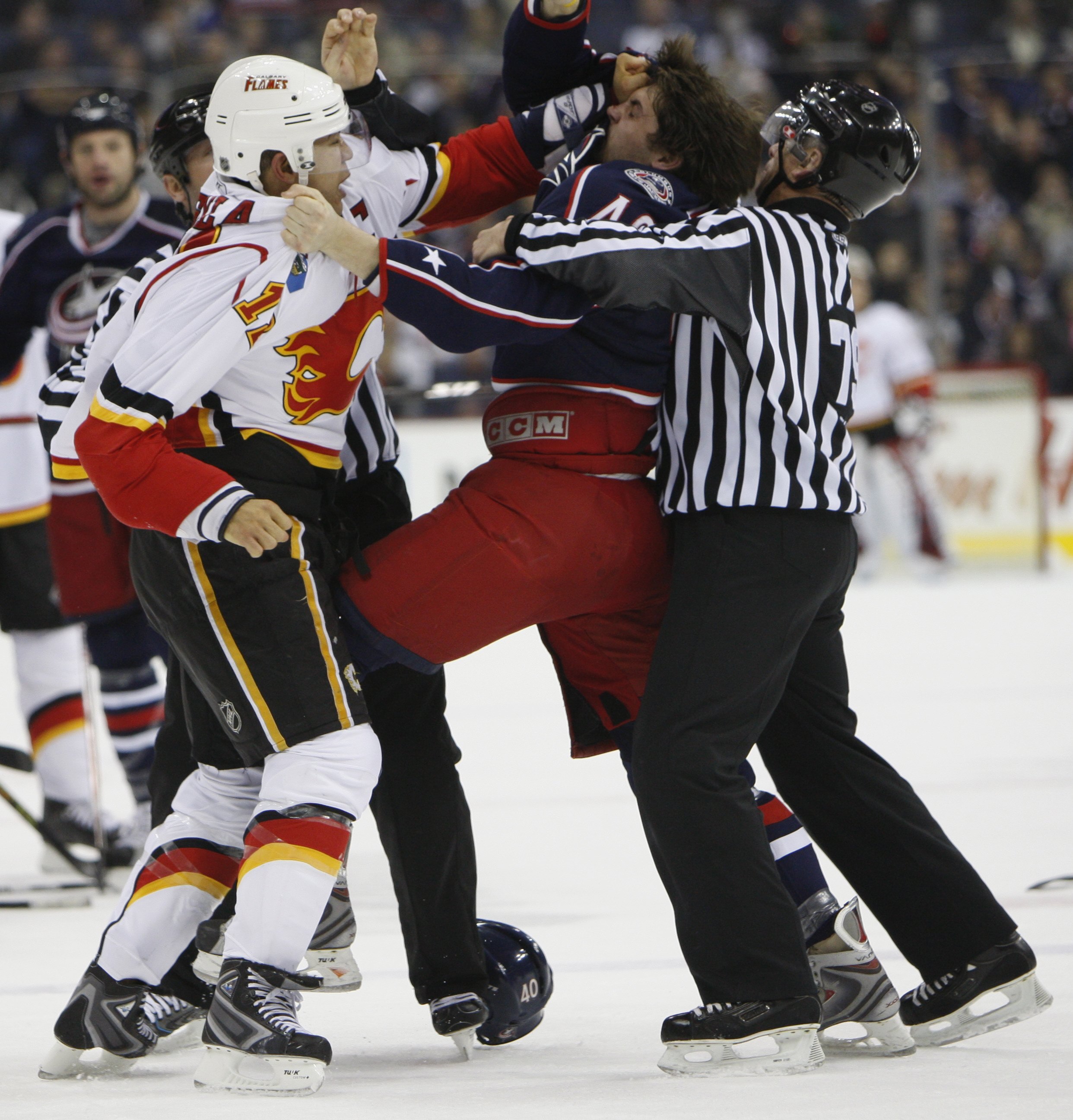 COLUMBUS, OH - DECEMBER 18:  Jarome Iginla #12 of the Calgary Flames fights against Jared Boll #40 of the Columbus Blue Jackets as linesman Mark Pare intervenes on December 18, 2007 at Nationwide Arena in Columbus, Ohio. (Photo by Gregory Shamus/Getty Ima