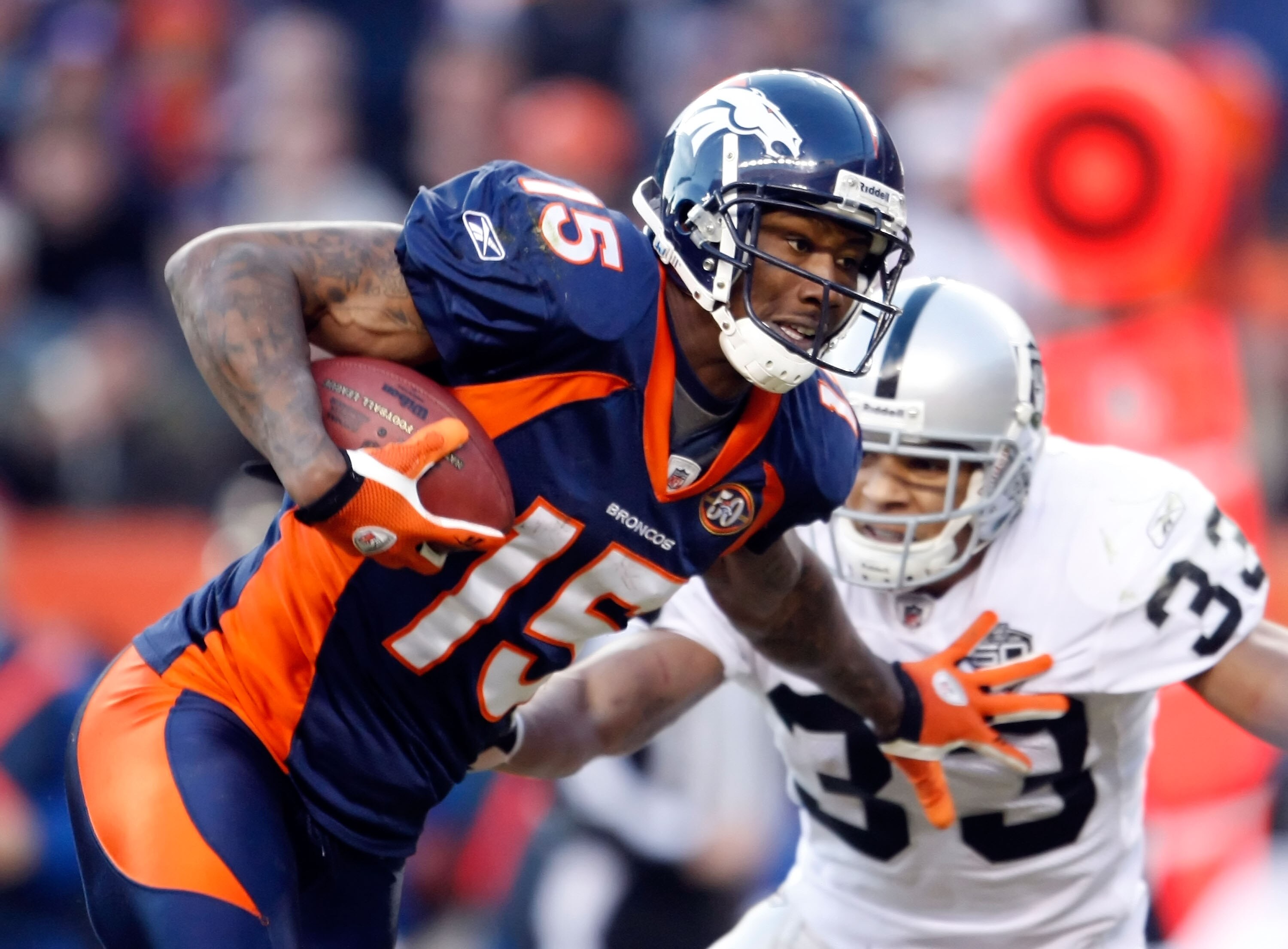 DENVER - DECEMBER 20:  Brandon Marshall #15 of the Denver Broncos stiff arms Tyvon Branch #33 of the Oakland Raiders in the second half at Invesco Field at Mile High on December 20, 2009 in Denver, Colorado. The Raiders defeated the Broncos 20-19.  (Photo