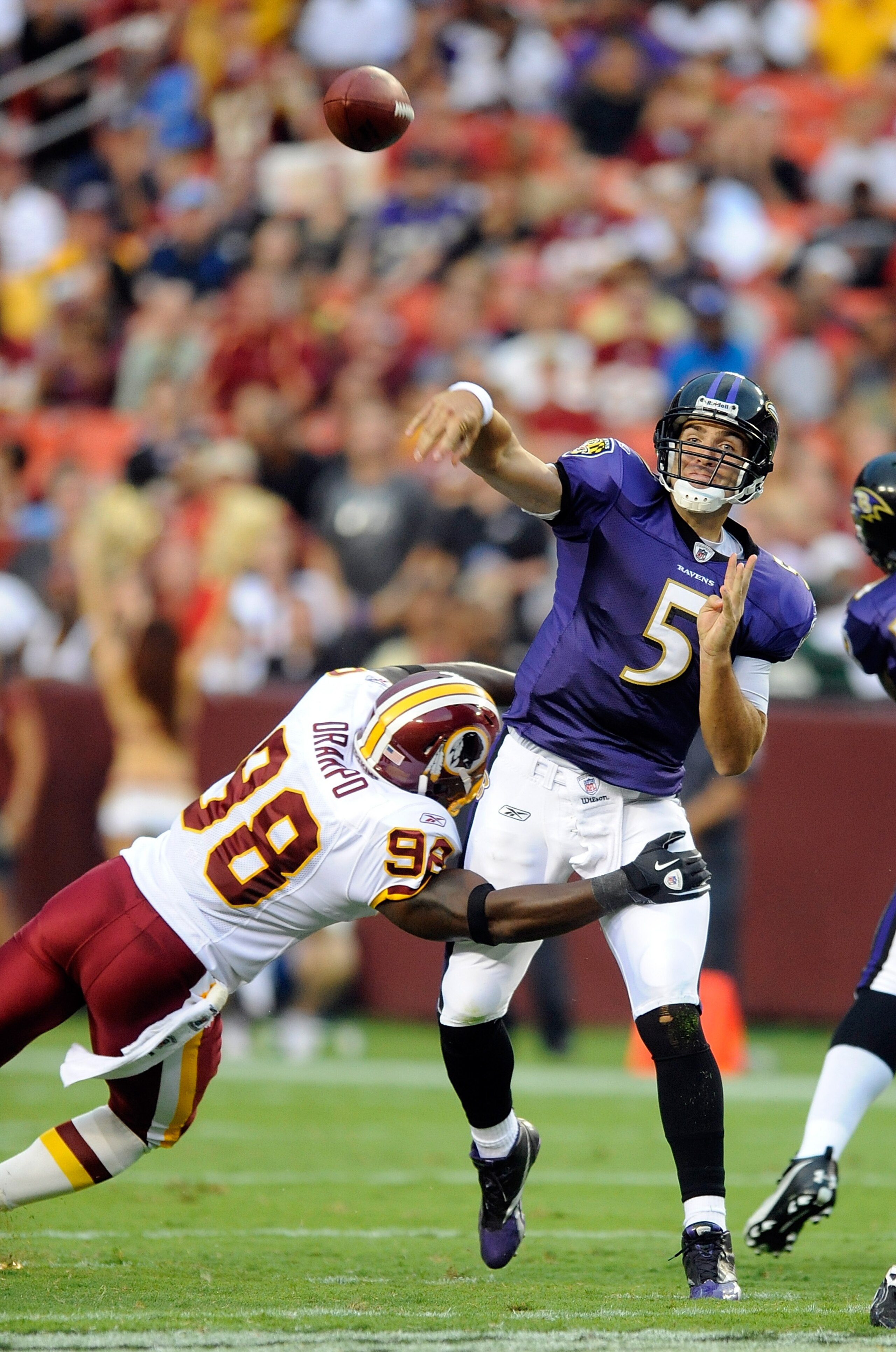 LANDOVER, MD - AUGUST 21:  Joe Flacco #5 of the Baltimore Ravens throws a pass during the preseason game as he is hit by Brian Orakpo #98 of the Washington Redskins at FedExField on August 21, 2010 in Landover, Maryland.  (Photo by Greg Fiume/Getty Images