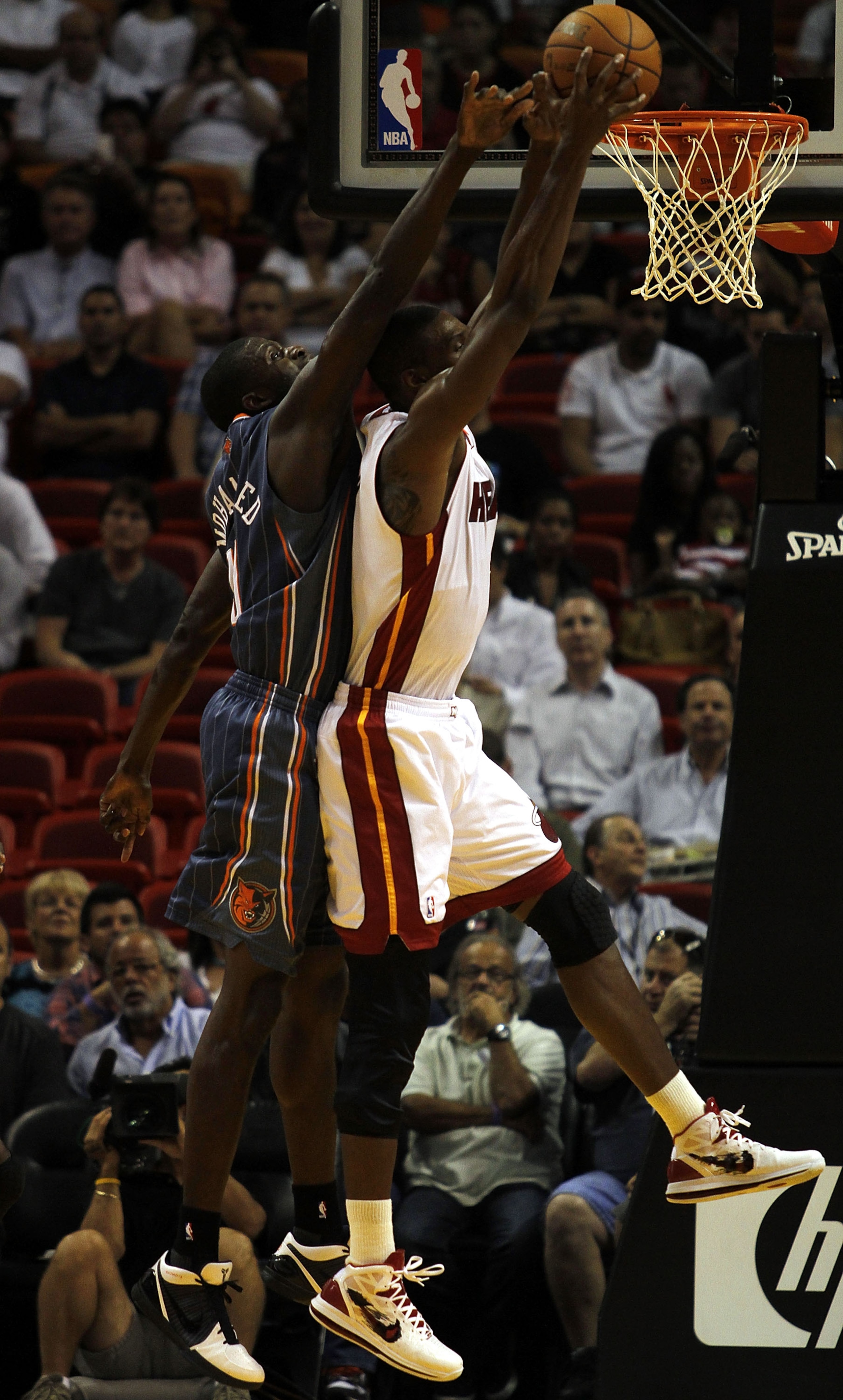 MIAMI - OCTOBER 18:  Forward Chris Bosh #1 of the Miami Heat rebounds against Center Nazr Mohammed #13 of the Charlotte Bobcats on October 18, 2010 at American Airlines Arena in Miami, Florida. NOTE TO USER: User expressly acknowledges and agrees that, by