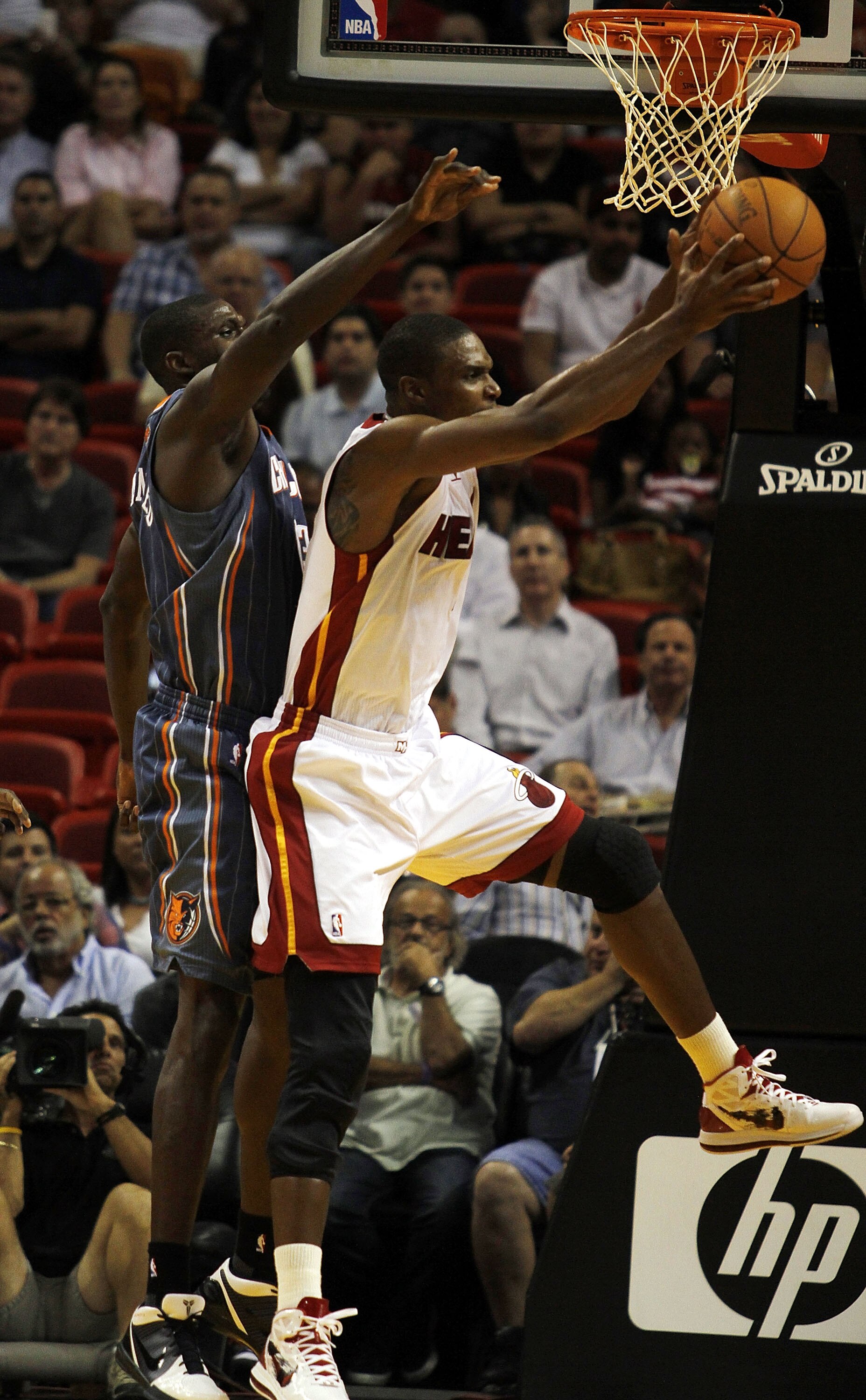 MIAMI - OCTOBER 18:  Forward Chris Bosh #1 of the Miami Heat rebounds against Center Nazr Mohammed #13 of the Charlotte Bobcats on October 18, 2010 at American Airlines Arena in Miami, Florida. NOTE TO USER: User expressly acknowledges and agrees that, by