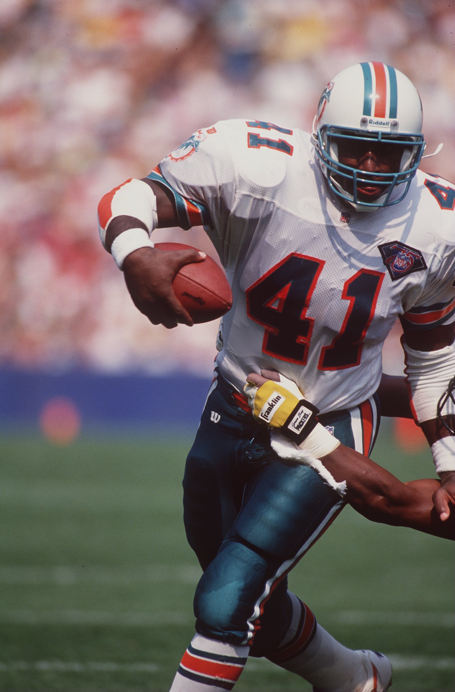 11 Sep 1994:  Running back Keith Byars of the Miami Dolphins looks up field as he uses his left arm to fend off an attempted tackle by a defensive player from the Green Bay Packers while running with the football during a carry in the Dolphins 24-14 victo