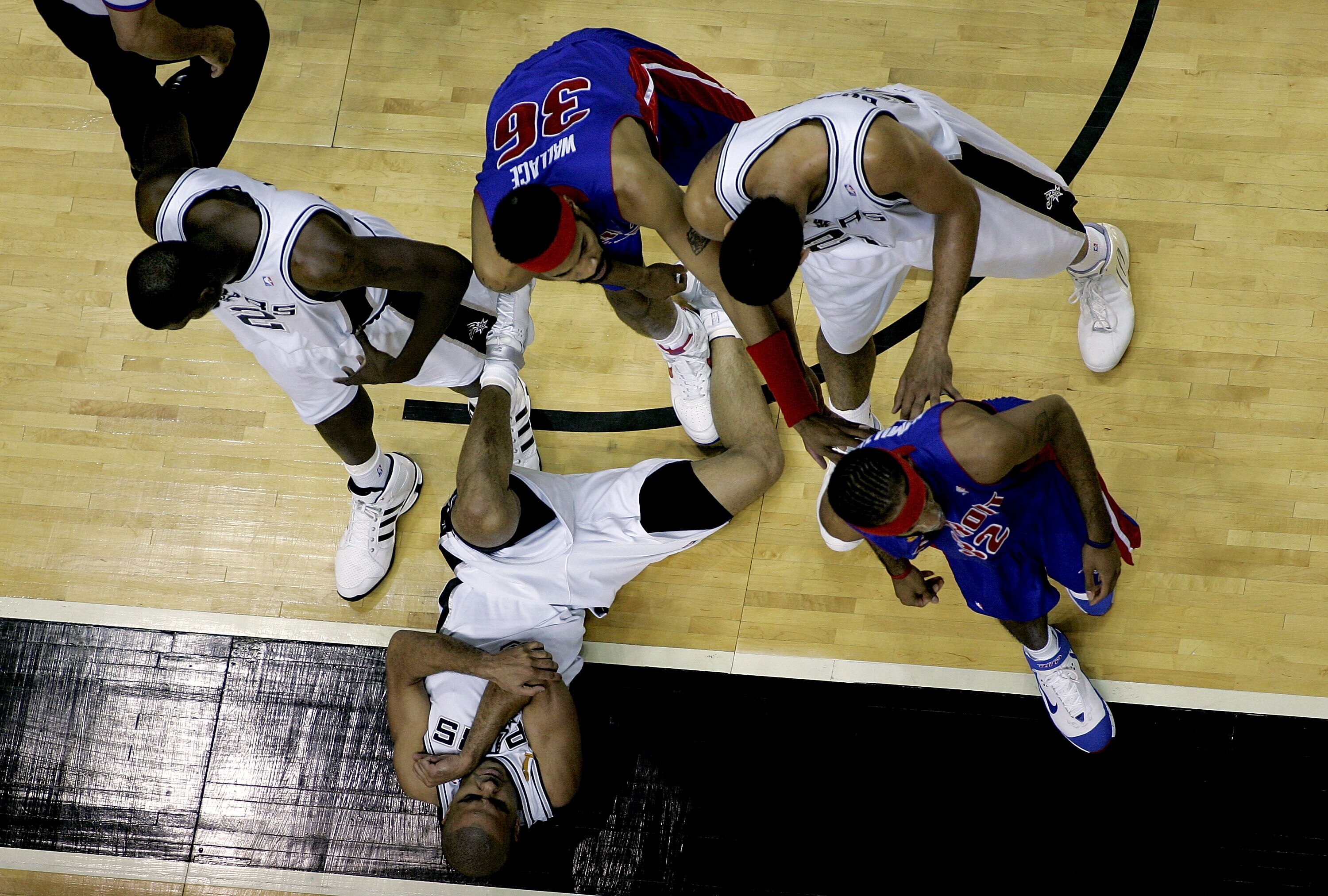 SAN ANTONIO - JUNE 21:  Tony Parker #9 of the San Antonio Spurs lays on the ground hurt as teammates Nazr Mohammed #2, Tim Duncan #21  and Rasheed Wallace #36 and Richard Hamilton #32 of the Detroit Pistons pause in the stoppage of play during the first h