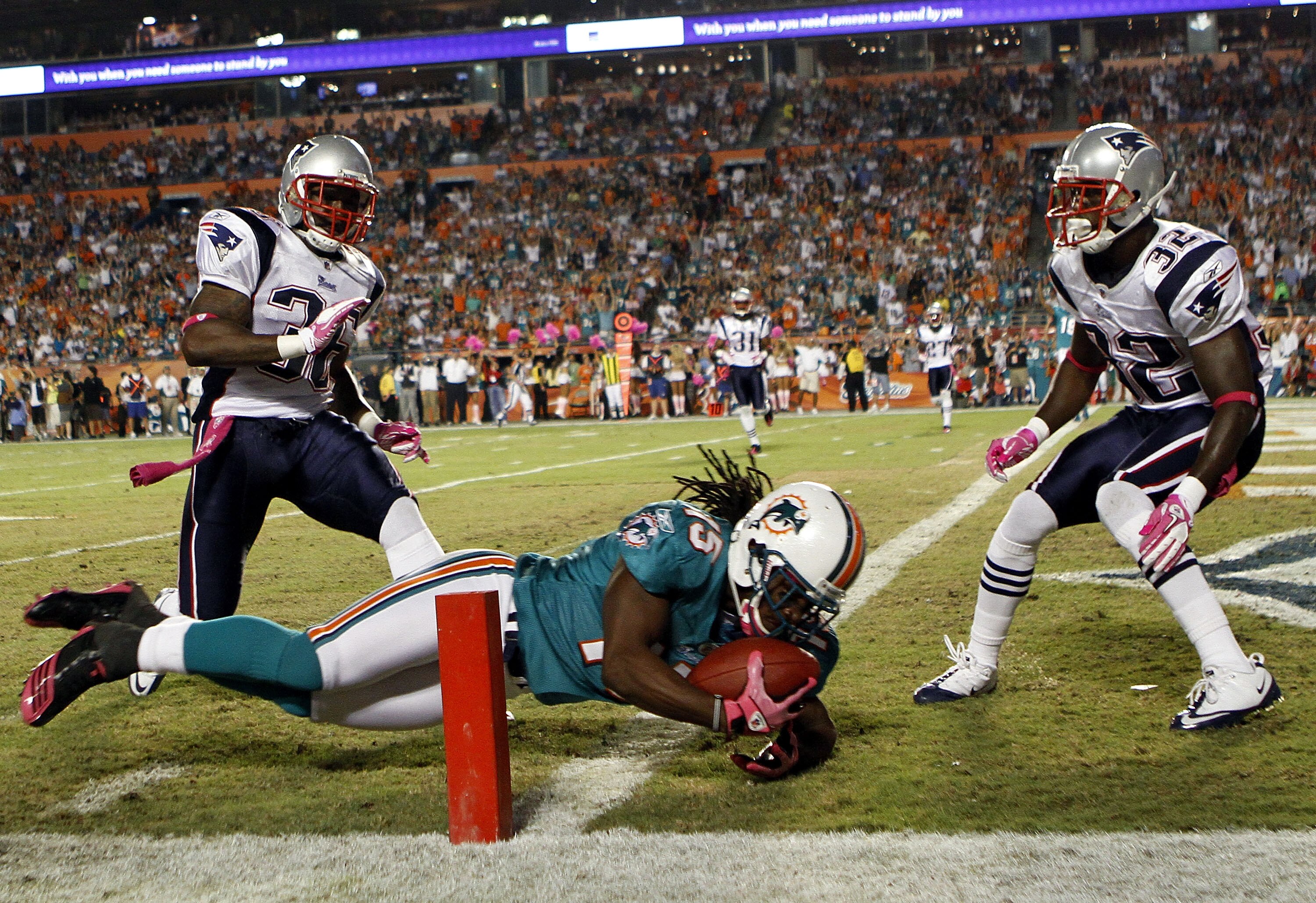 MIAMI - OCTOBER 04:  Receiver Davone Bess #15 of the Miami Dolphins scores a touchdown against James Sanders #36 and Devin McCorty #32 of the New England Patriots at Sun Life Stadium on October 4, 2010 in Miami, Florida.  (Photo by Marc Serota/Getty Image