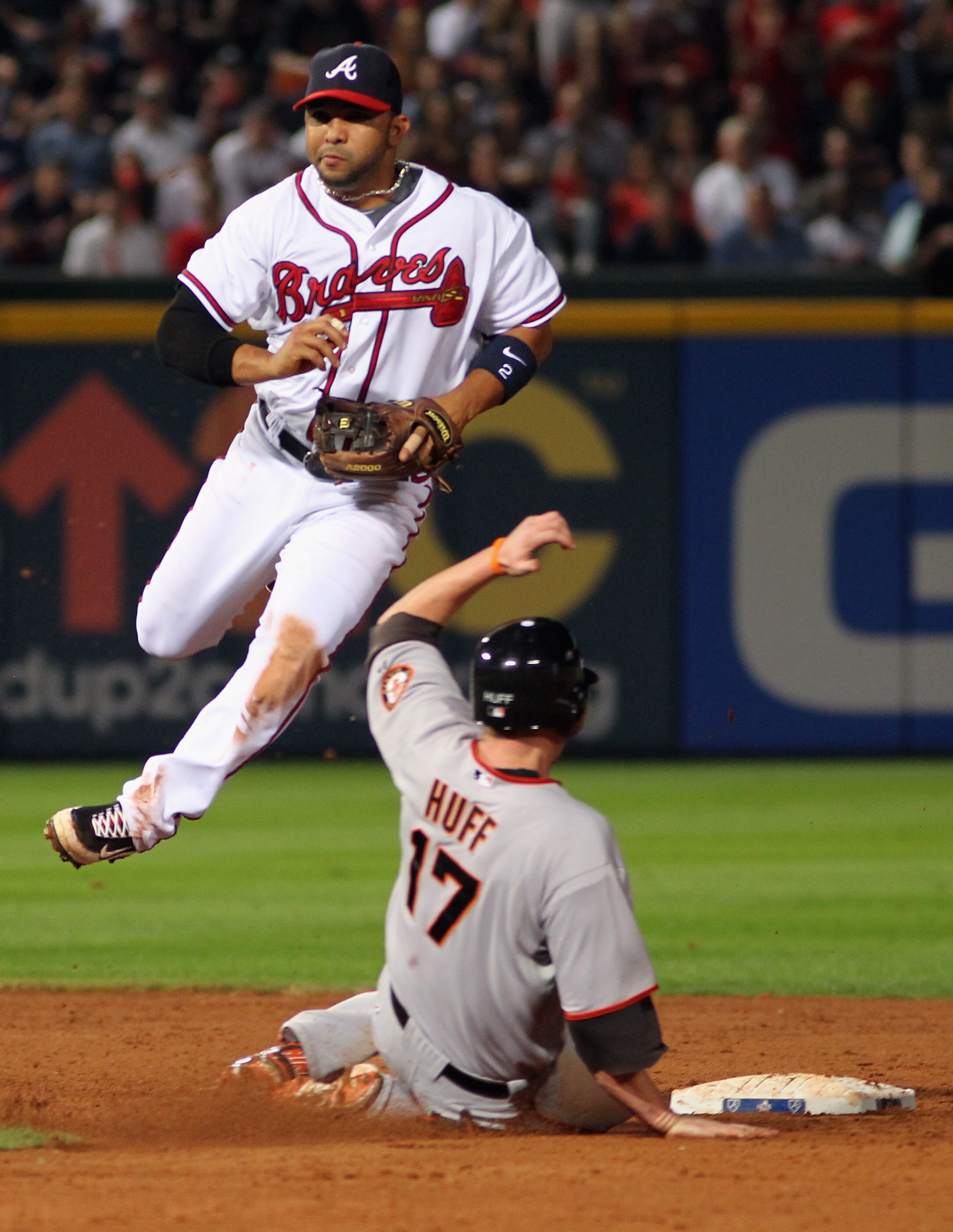 ATLANTA - OCTOBER 11:  Shortstop Alex Gonzalez #2 of the Atlanta Braves turns a double play as Aubrey Huff #17 of the San Francisco Giants approaches second during the 9th inning of Game Four of the NLDS of the 2010 MLB Playoffs on October 11, 2010  at Tu
