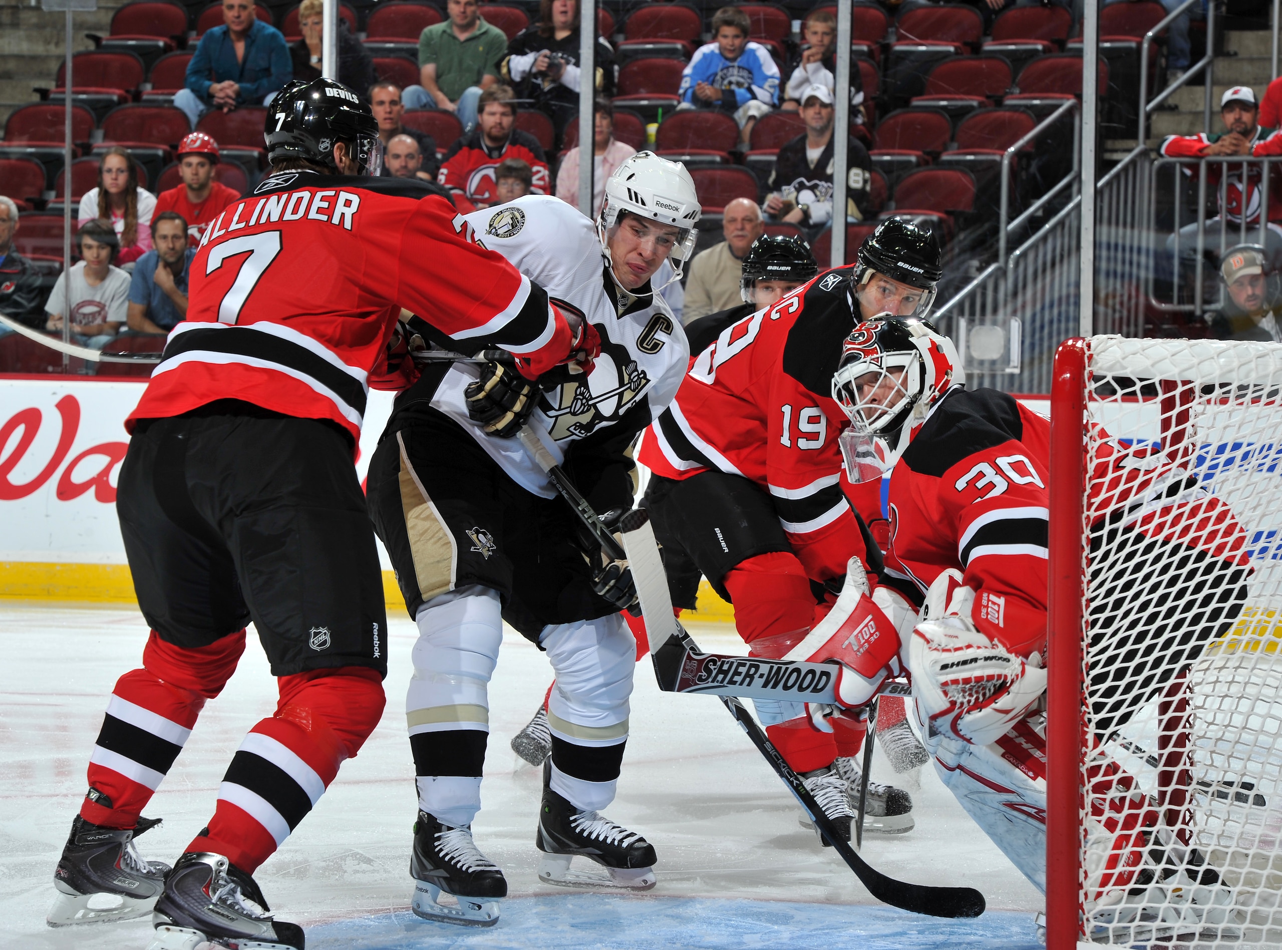 NEWARK, NJ - OCTOBER 11: Sidney Crosby #87 of the Pittsburgh Penguins is cross checked by Henrik Tallinder #7 of the New Jersey Devils in front of goaltender Martin Brodeur #30 of the New Jersey Devils during the first period at the Prudential Center on O