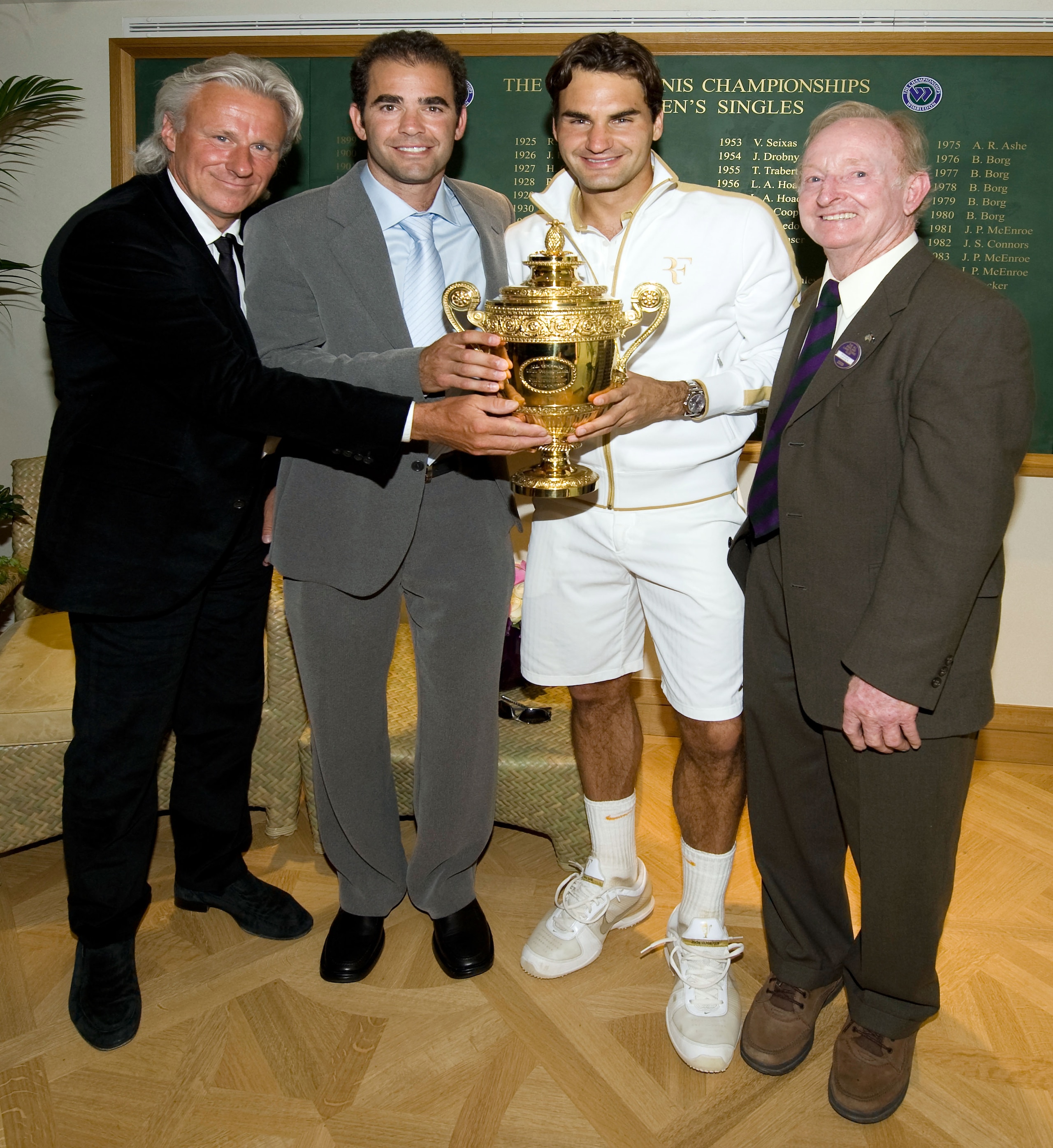 WIMBLEDON, ENGLAND - JULY 05:  Roger Federer of Switzerland (2R) celebrates with the trophy alongside Bjorn Borg (L), Pete Sampras (2L) and Rod Laver (R)  after the men's singles final match against Andy Roddick of USA on Day Thirteen of the Wimbledon Law
