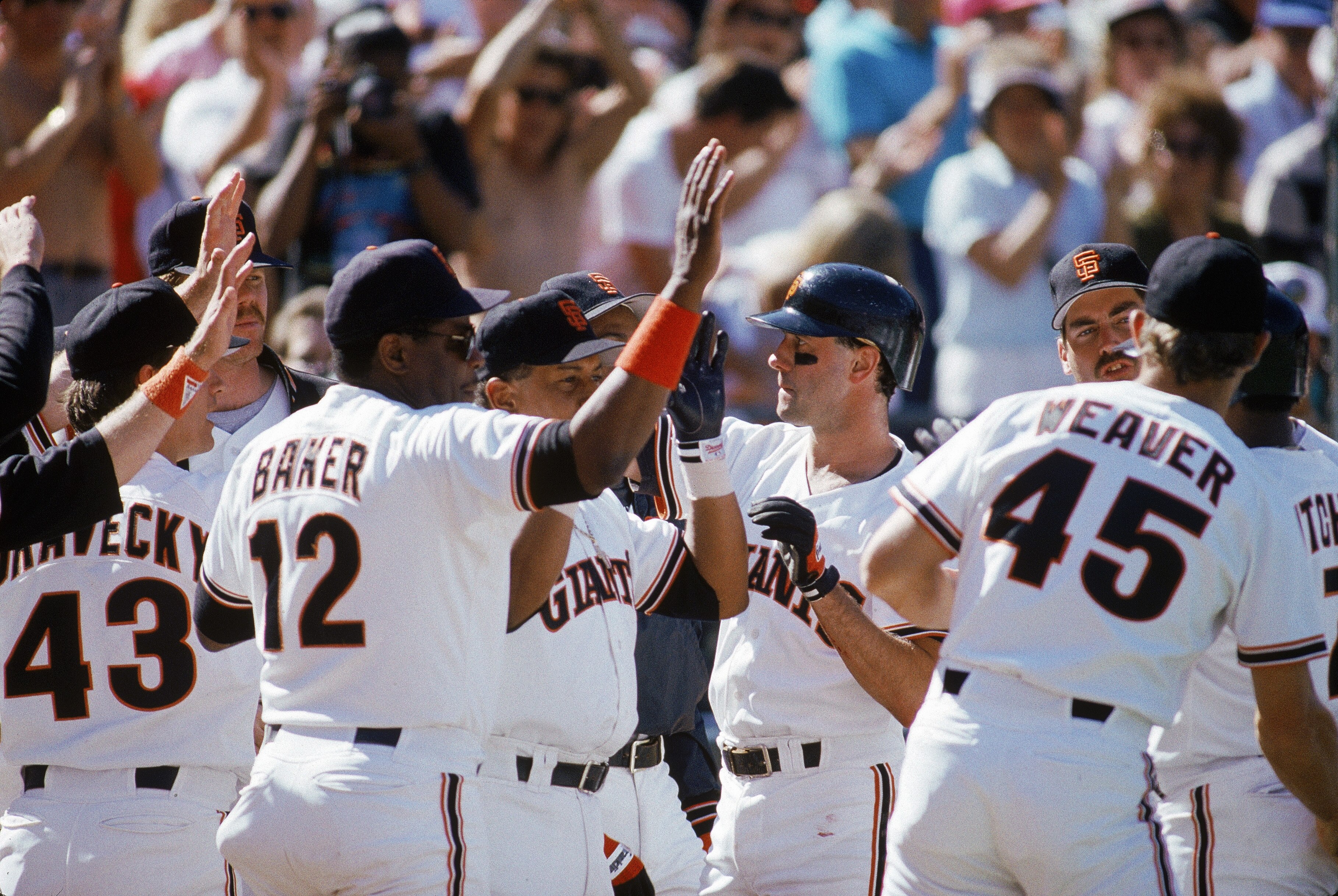 SAN FRANCISCO - OCTOBER:  Manager Dusty Baker #12 and Will Clark #22 of the San Francisco Giants high five teammates against the Chicago Cubs during the 1989 National League Championship Series at Candlestick Park in October 1989 in San Francisco, Califor