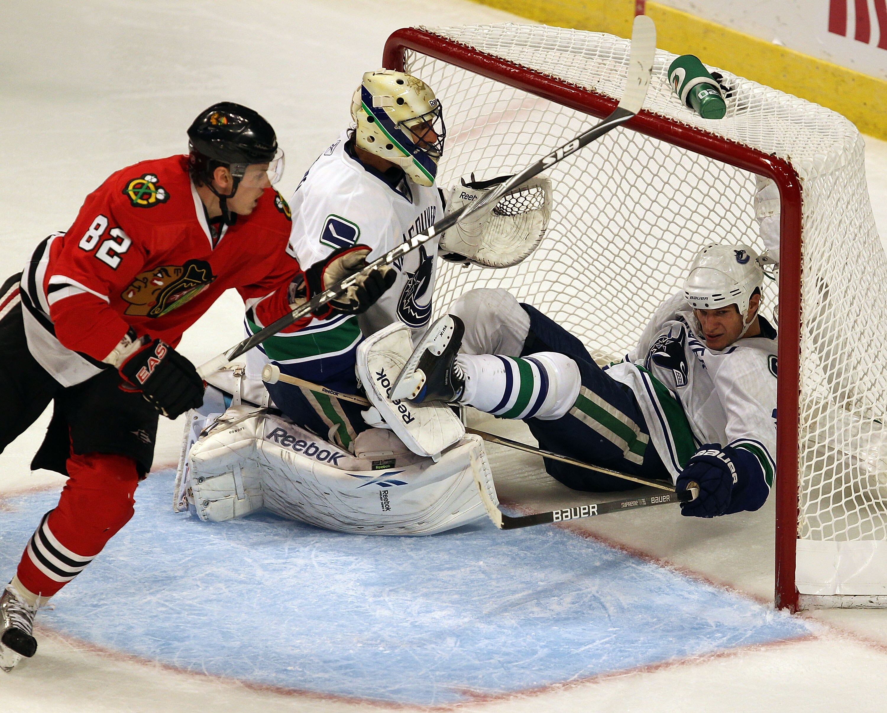 CHICAGO - OCTOBER 20: Kevin Bieksa #3 of the Vancouver Canucks falls over Roberto Luongo #1 on an interference call against Tomas Kopecky #82 of the Chicago Blackhawks at the United Center on October 20, 2010 in Chicago, Illinois. (Photo by Jonathan Danie