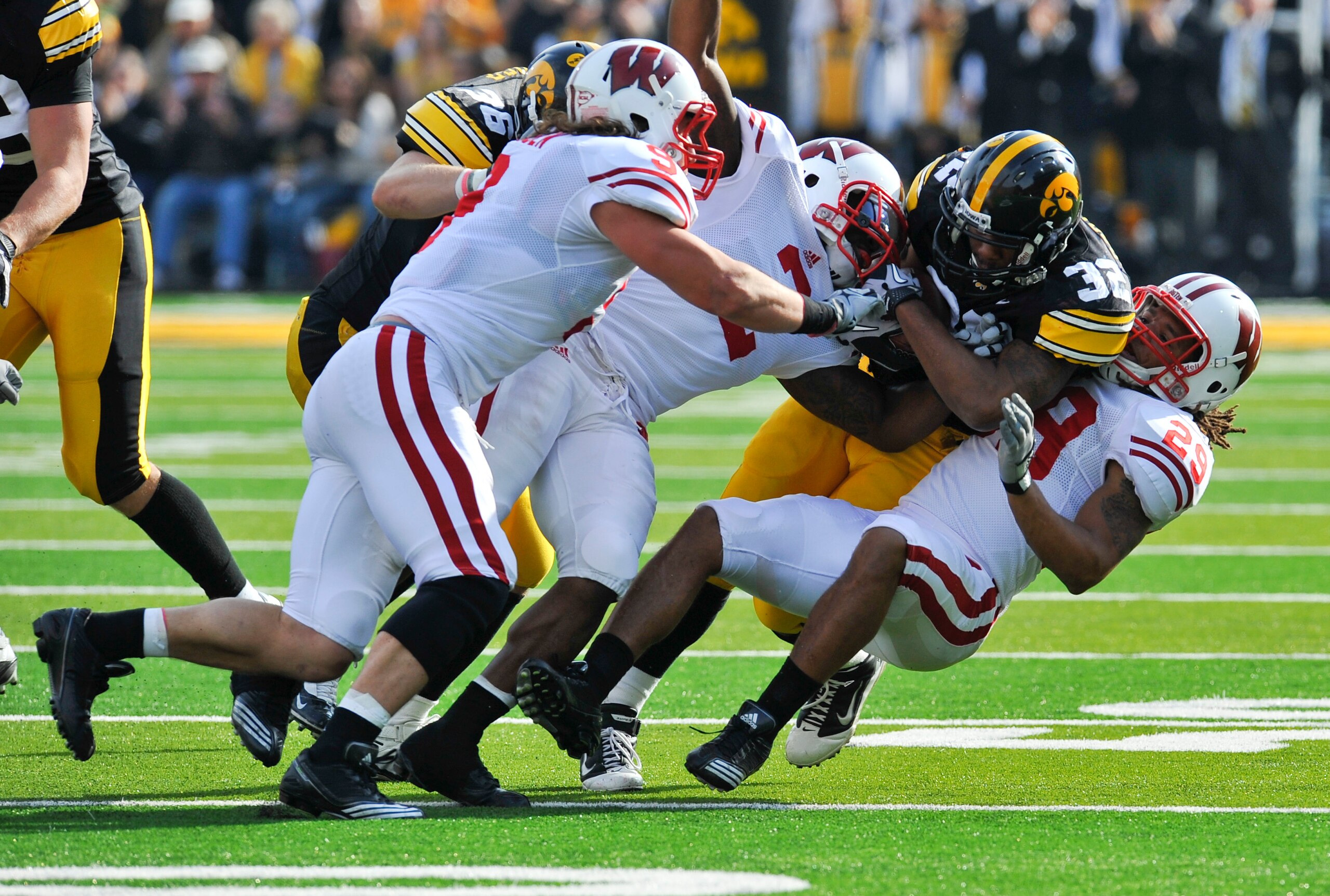 IOWA CITY, IA - OCTOBER 23: Running back Adam Robinson #32 of the University of Iowa Hawkeyes is tackled by defensive backs Jay Valai #2 and Nile Brinkley #29 and linebacker Blake Sorensen #9 of the Wisconsin Badgers during the first half of play at Kinni