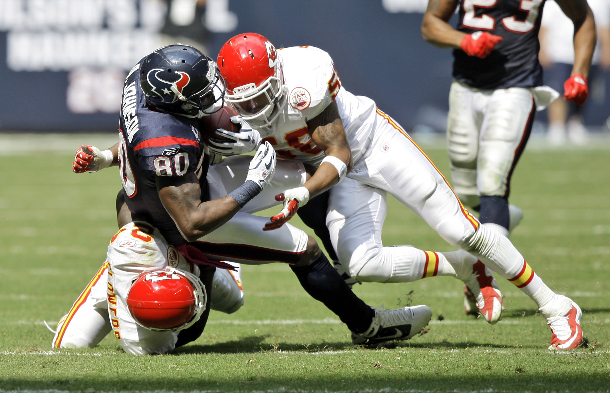 HOUSTON - OCTOBER 17:  Andre Johnson #80 of the Houston Texans is brought down by linebacker Jovan Belcher #59 and cornerback Brandon Flowers #24 at Reliant Stadium on October 17, 2010 in Houston, Texas.  (Photo by Bob Levey/Getty Images)