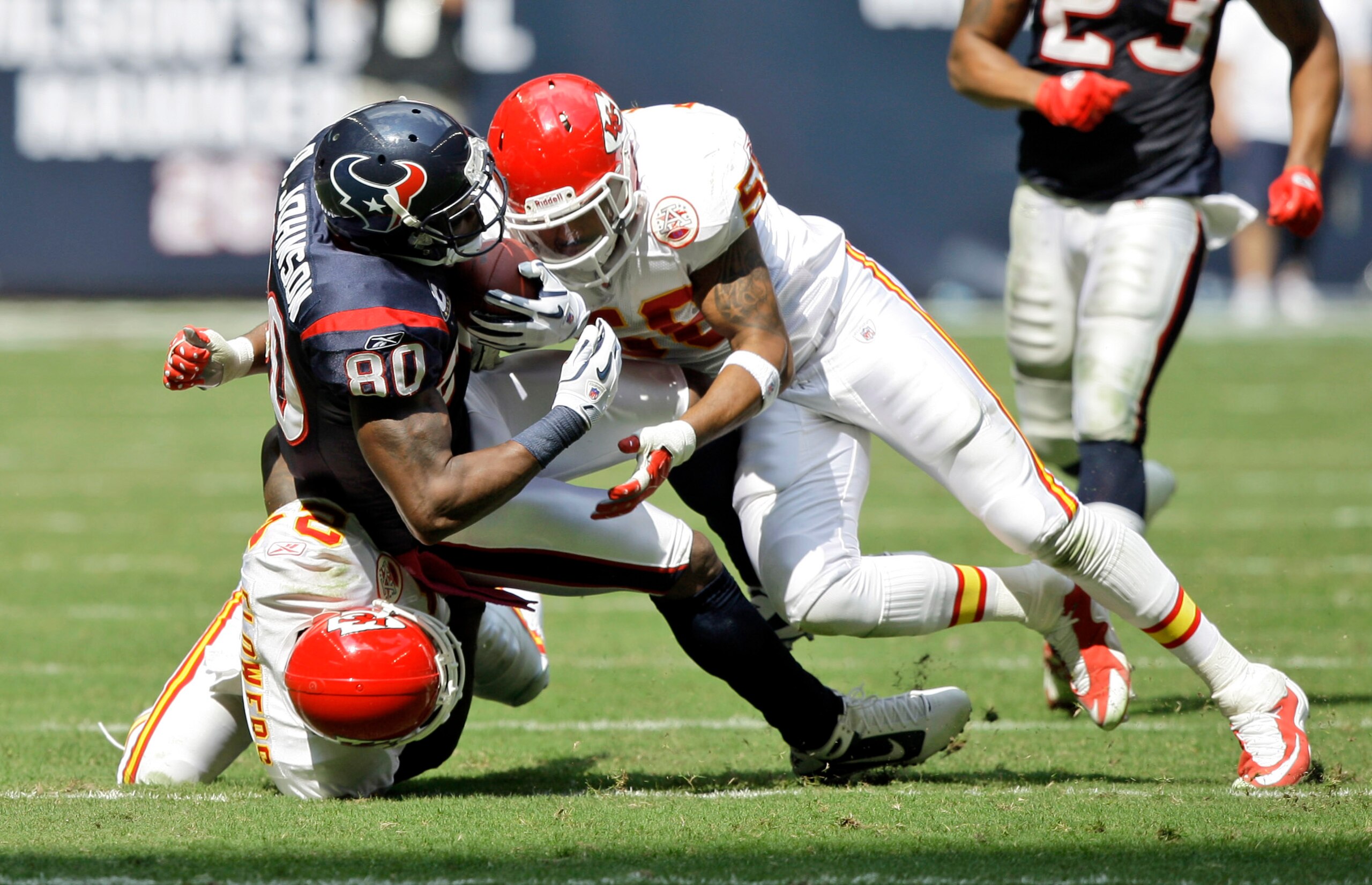 HOUSTON - OCTOBER 17:  Andre Johnson #80 of the Houston Texans is brought down by linebacker Jovan Belcher #59 and cornerback Brandon Flowers #24 at Reliant Stadium on October 17, 2010 in Houston, Texas.  (Photo by Bob Levey/Getty Images)