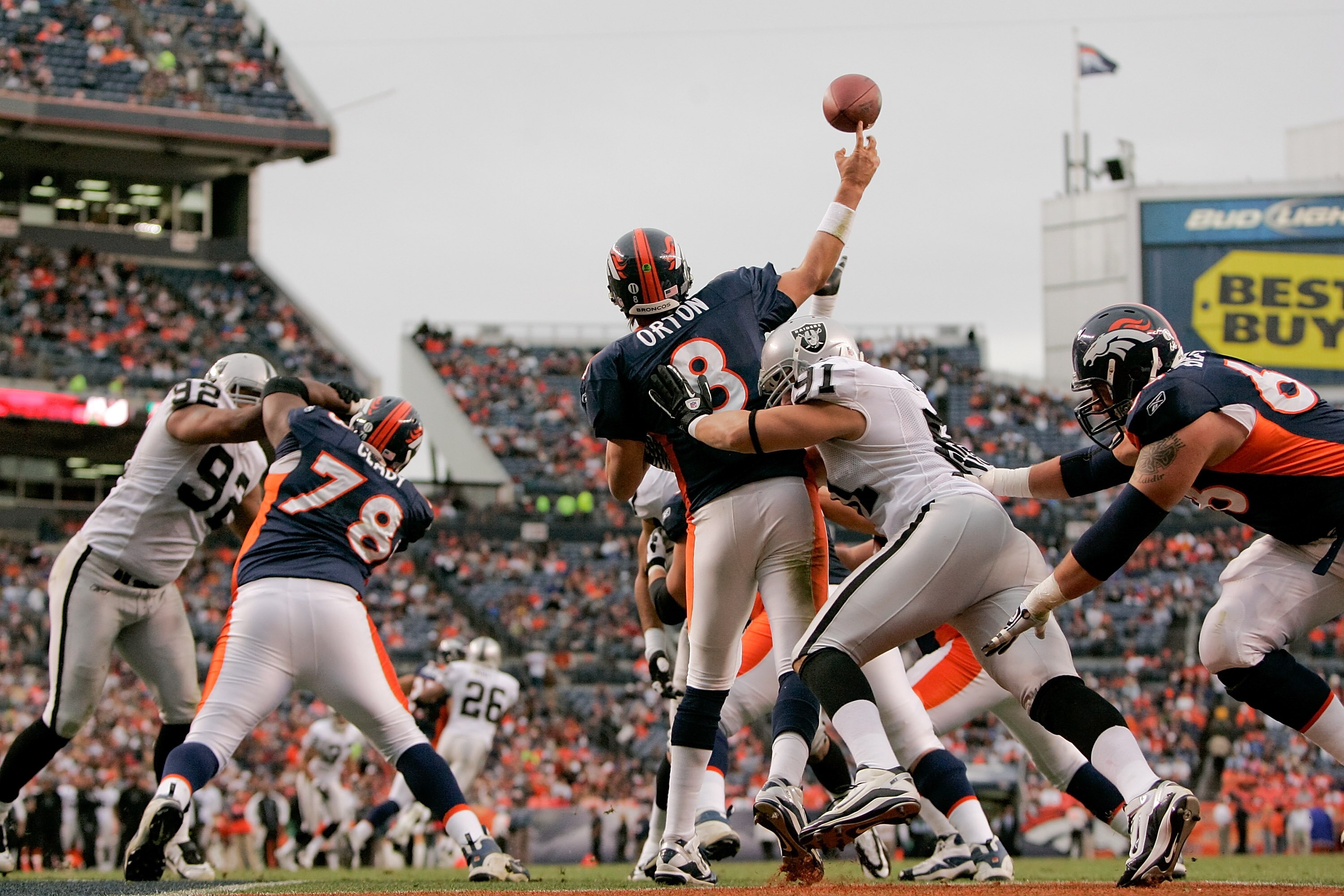 DENVER - OCTOBER 24:  Quarterback Kyle Orton #8 of the Denver Broncos is hit as he makes a pass from his own end zone by defensive end Trevor Scott #91 of the Oakland Raiders at INVESCO Field at Mile High on October 24, 2010 in Denver, Colorado. The Raide