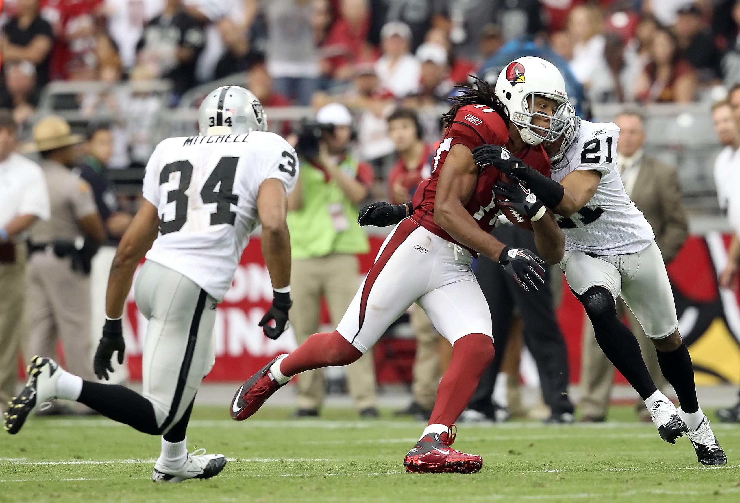 GLENDALE, AZ - SEPTEMBER 26:  Runningback Larry Fitzgerald #11 of the Arizona Cardinals runs with the football after a reception against Nnamdi Asomugha #21 and Mike Mitchell #34 of the Oakland Raiders during the third quarter of the NFL game at the Unive