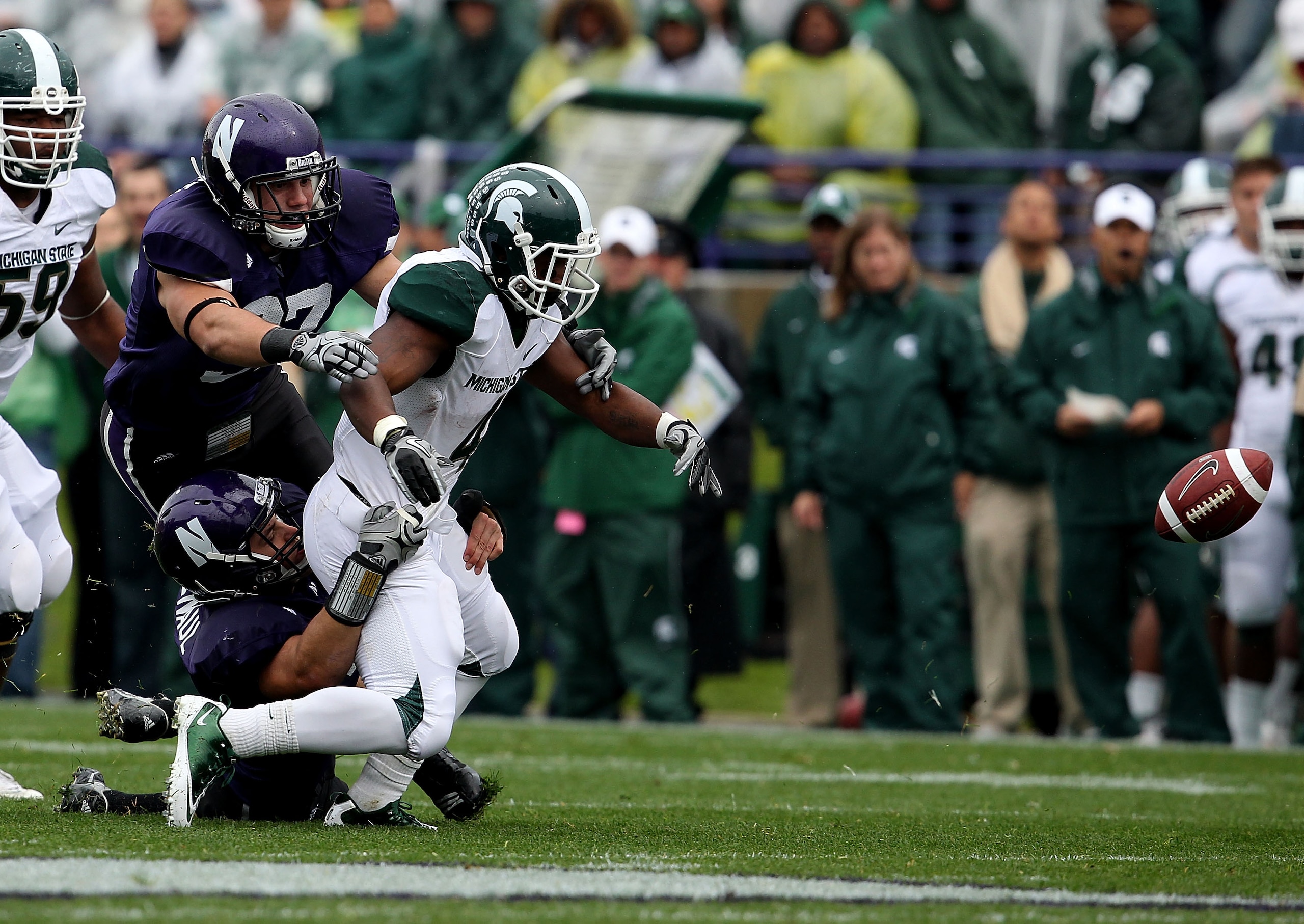 EVANSTON, IL - OCTOBER 23: Edwin Baker #4 of the Michigan State Spartans fumbles the ball as he is hit by Bryce McNaul #51 and Tyler Scott #97 of the Northwestern Wildcats at Ryan Field on October 23, 2010 in Evanston, Illinois. Michigan State defeated No