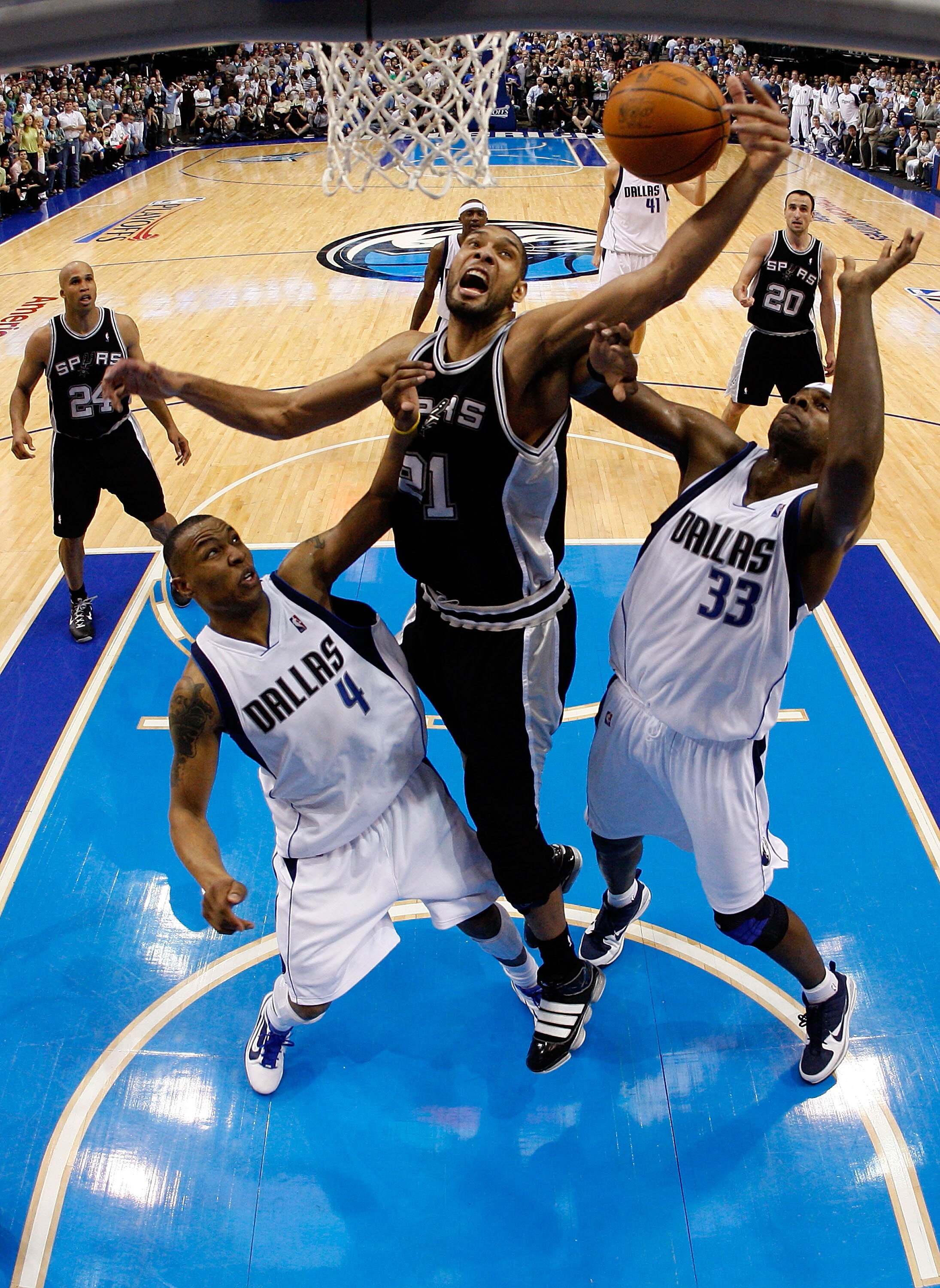 DALLAS - APRIL 21:  Forward Tim Duncan #21 of the San Antonio Spurs grabs a rebound against Caron Butler #4 and Brendan Haywood #33 of the Dallas Mavericks in Game Two of the Western Conference Quarterfinals during the 2010 NBA Playoffs at American Airlin