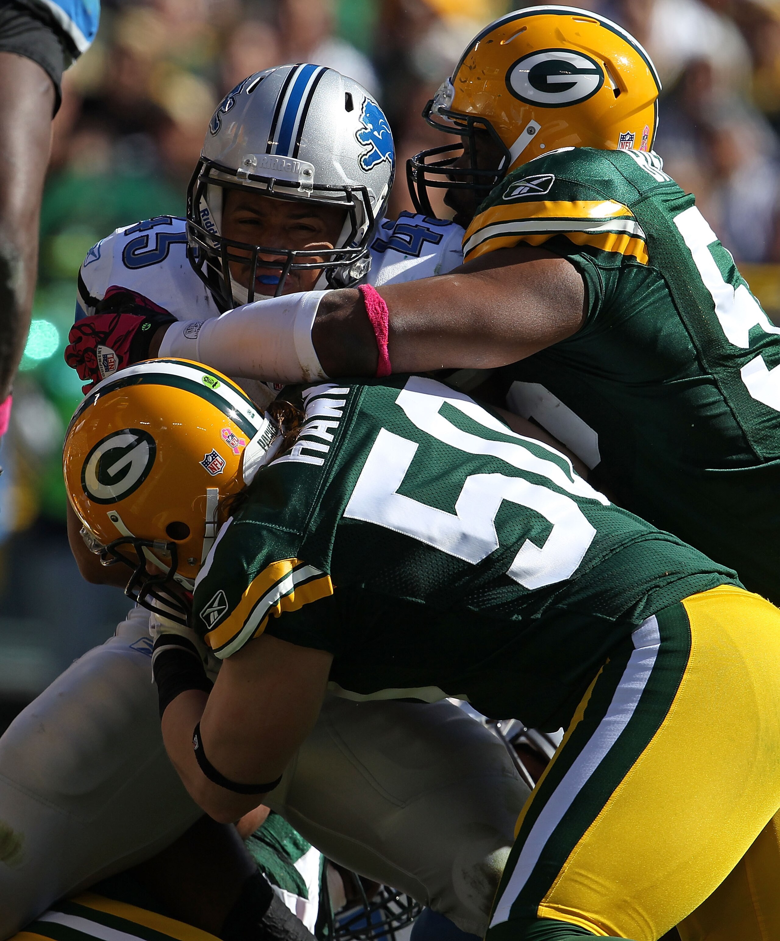 GREEN BAY, WI - OCTOBER 03: A.J. Hawk #50 and Desmond Bishop #55 of the Green Bay Packers tackle Jerome Felton #45 of the Detroit Lions at Lambeau Field on October 3, 2010 in Green Bay, Wisconsin. The Packers defeated the Lions 28-26. (Photo by Jonathan D