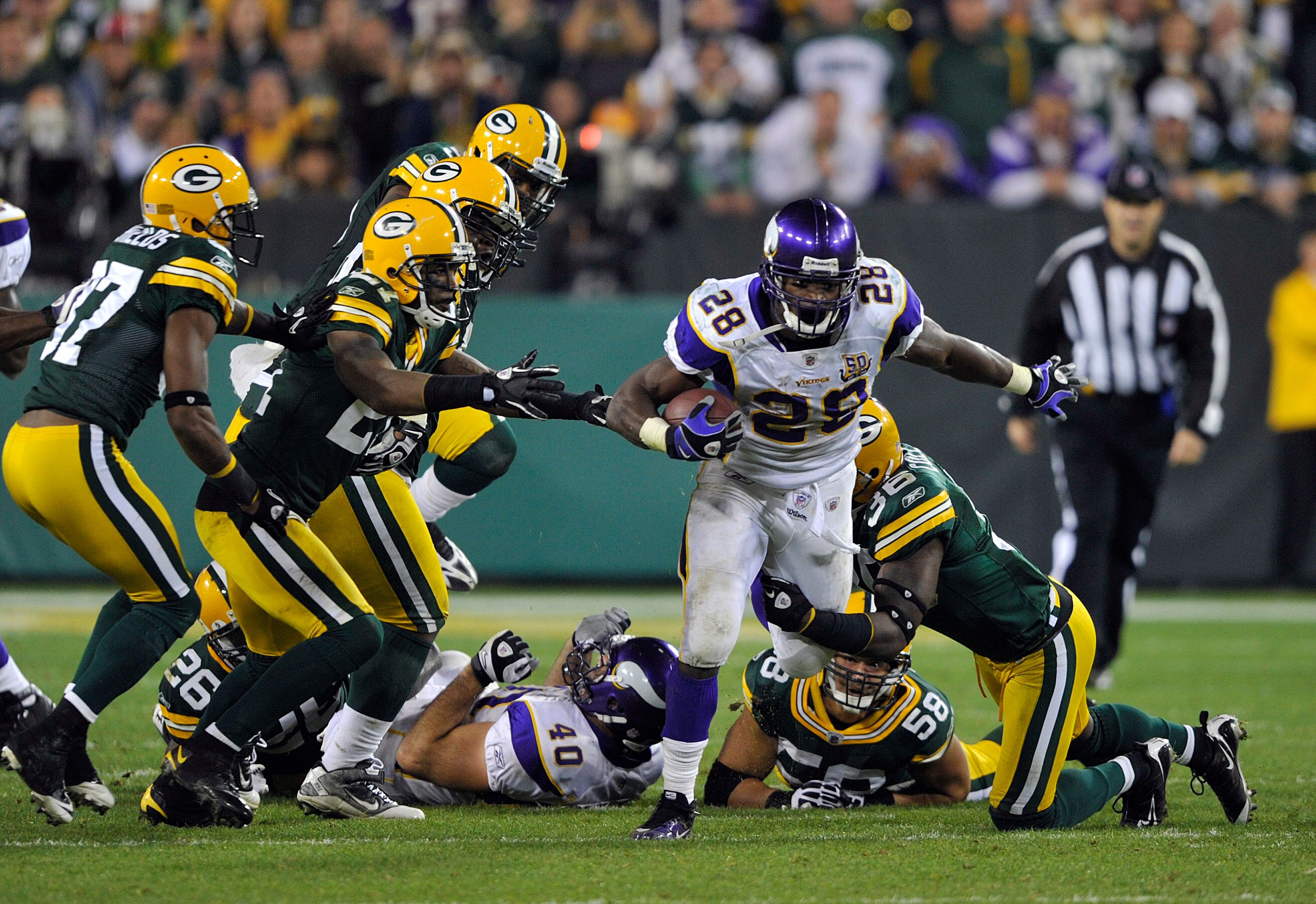 GREEN BAY, WI - OCTOBER 24:  Adrian Peterson #28 of the Minnesota Vikings breaks through the Green Bay Packers defense during their game at Lambeau Field on October 24, 2010 in Green Bay, Wisconsin. (Photo by Jim Prisching/Getty Images)
