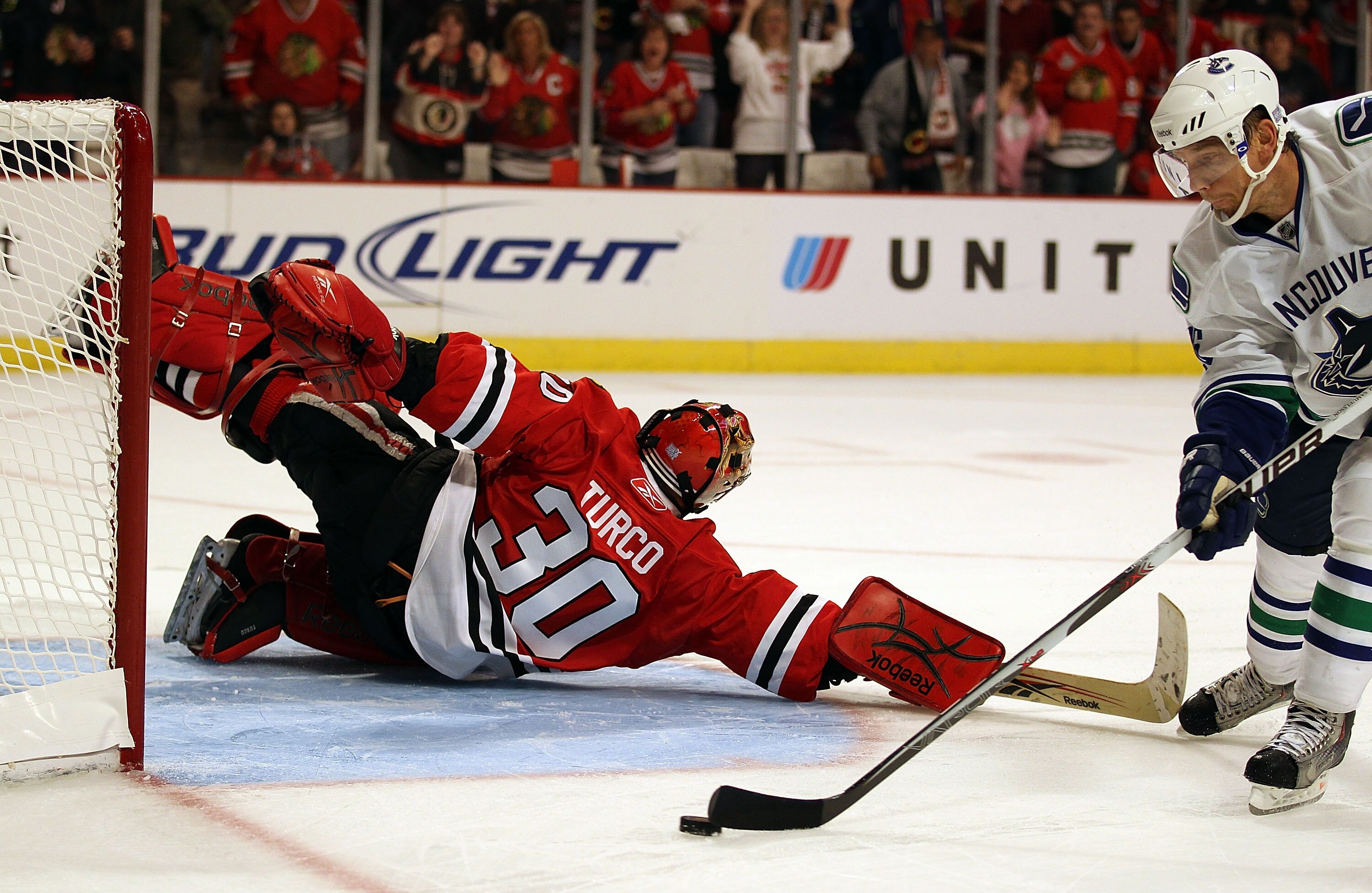 CHICAGO - OCTOBER 20: Marty Turco #30 of the Chicago Blackhawks dives to save the puck on a shot by Mikael Samuelsson #26 of the Vancouver Canucks in the shootout phase at the United Center on October 20, 2010 in Chicago, Illinois. The Blackhawks defeated