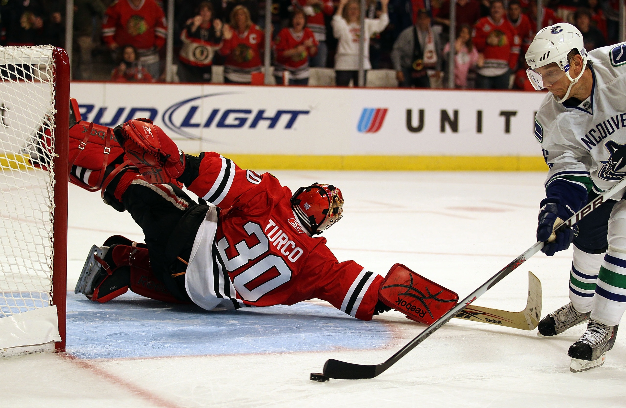 CHICAGO - OCTOBER 20: Marty Turco #30 of the Chicago Blackhawks dives to save the puck on a shot by Mikael Samuelsson #26 of the Vancouver Canucks in the shootout phase at the United Center on October 20, 2010 in Chicago, Illinois. The Blackhawks defeated
