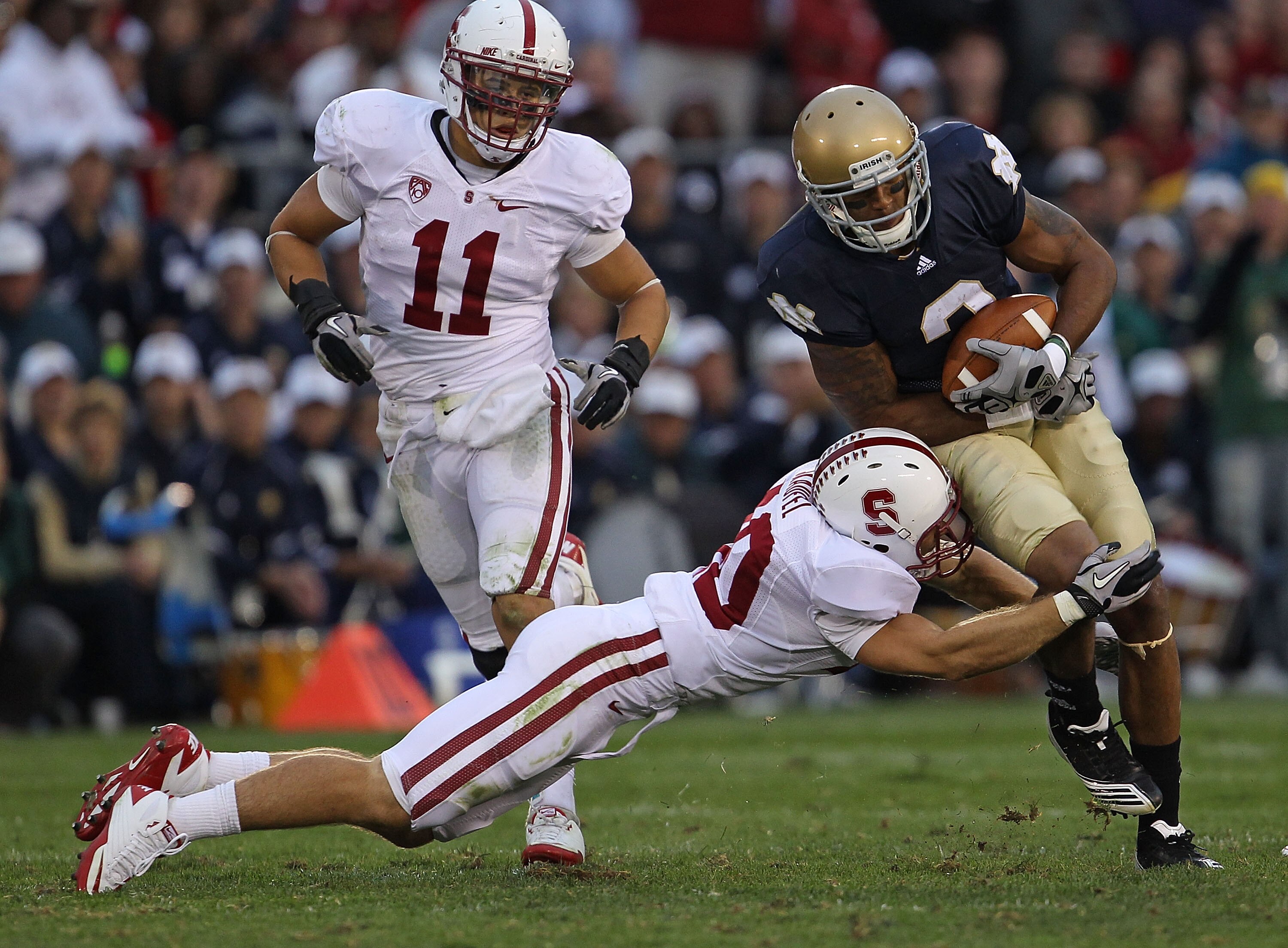 SOUTH BEND, IN - SEPTEMBER 25: Taylor Skaufel #40 of the Stanford Cardinal tackles Michael Floyd #3 of the Notre Dame Fighting Irish as Shayne Skov #11 closes in at Notre Dame Stadium on September 25, 2010 in South Bend, Indiana. Stanford defeated Notre D
