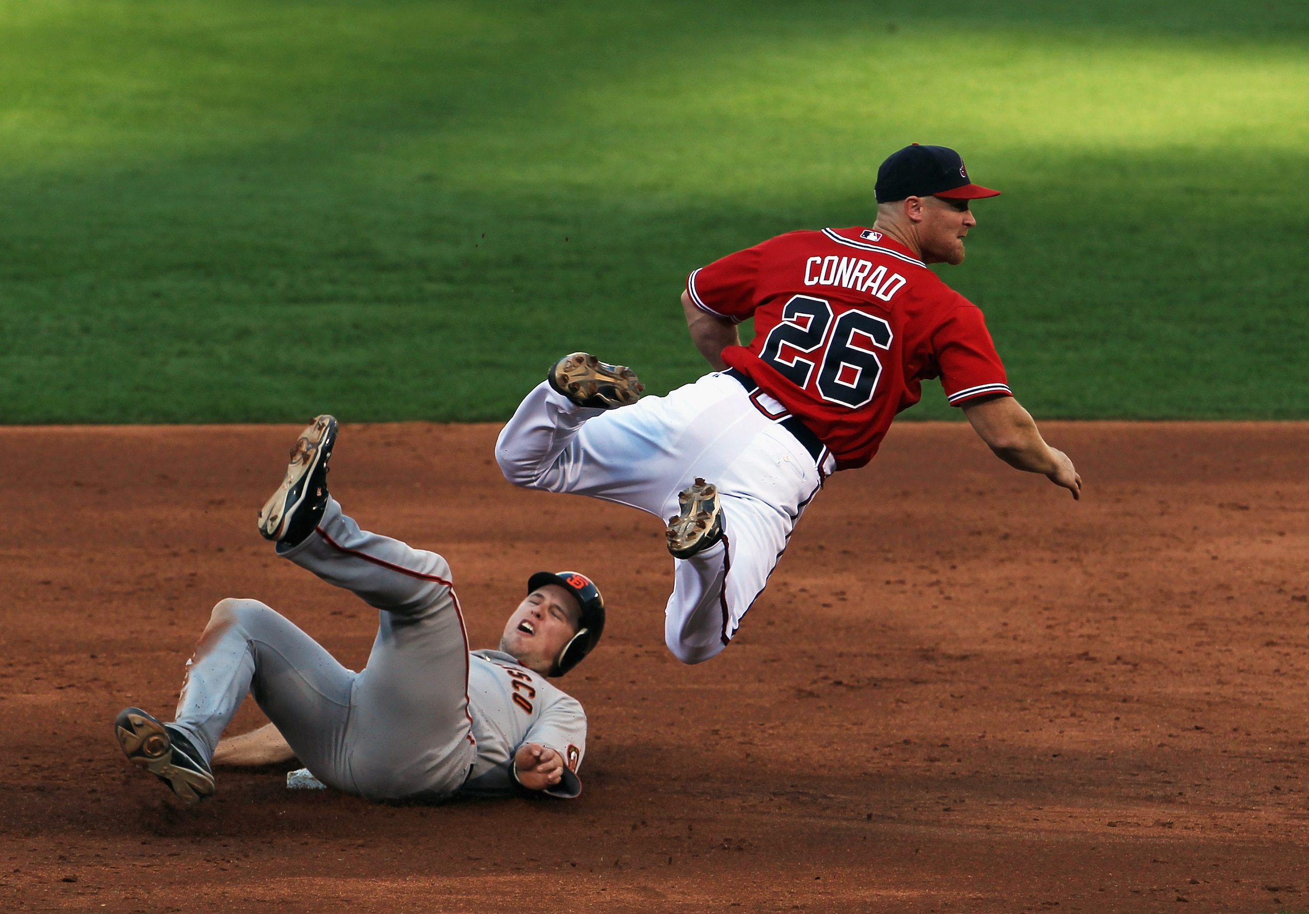 ATLANTA - OCTOBER 10:  Brooks Conrad #26 of the Atlanta Braves evades a sliding Buster Posey #28 of  the San Francisco Giants while turning a double play during Game Three of the NLDS of the 2010 MLB Playoffs on October 10, 2010 at Turner Field in Atlanta