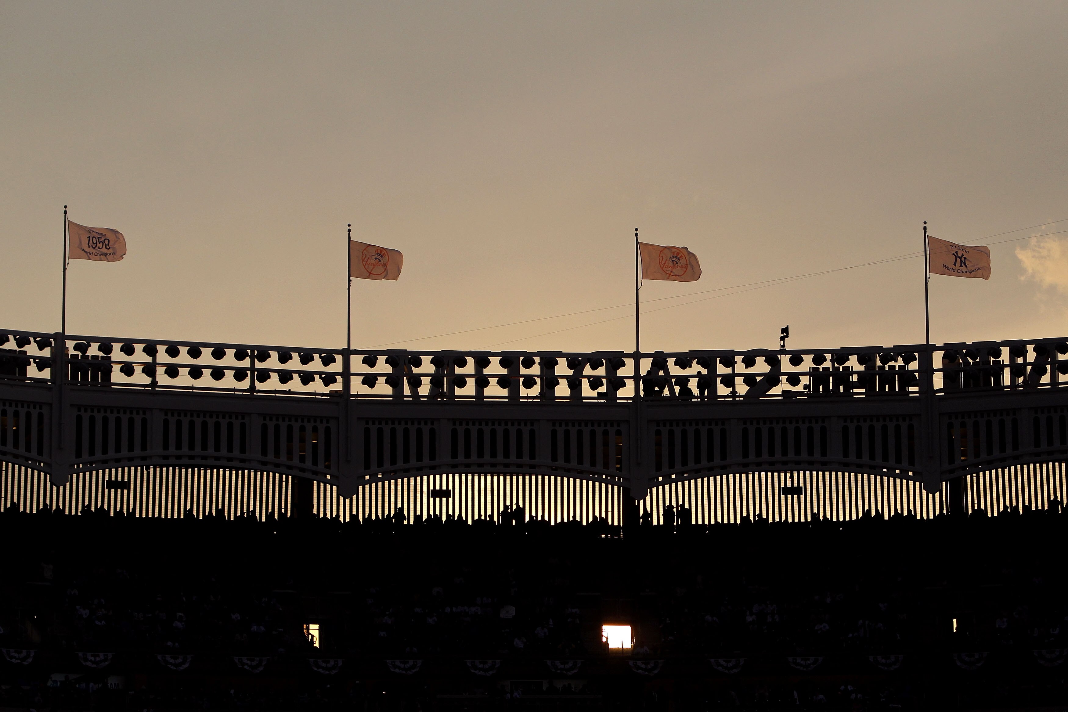 NEW YORK - OCTOBER 20:  Flags fly over the facade atop Yankee Stadium as the New York Yankees play against the Texas Rangers in Game Five of the ALCS during the 2010 MLB Playoffs at Yankee Stadium on October 20, 2010 in the Bronx borough of New York City.