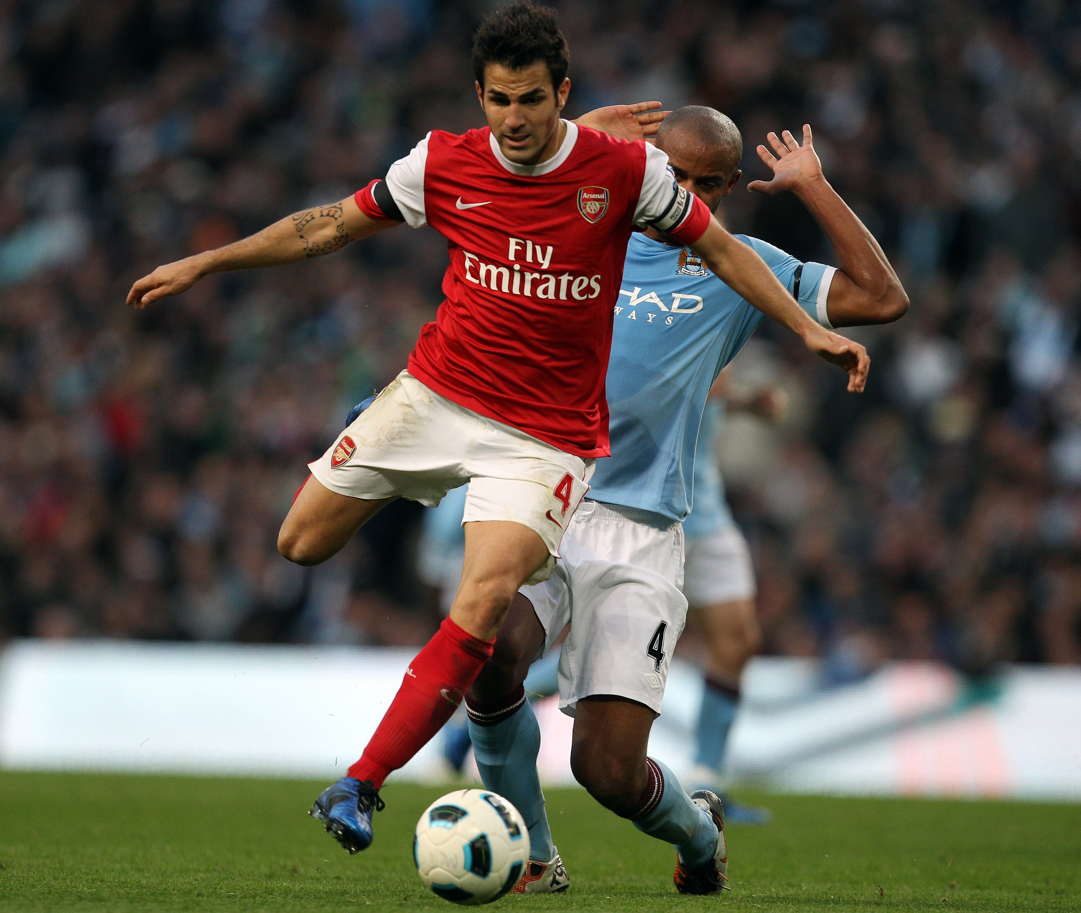 MANCHESTER, ENGLAND - OCTOBER 24:  Cesc Fabregas of Arsenal holds off Vincent Kompany of City during the Barclays Premier League match between Manchester City and Arsenal at City of Manchester Stadium on October 24, 2010 in Manchester, England.  (Photo by