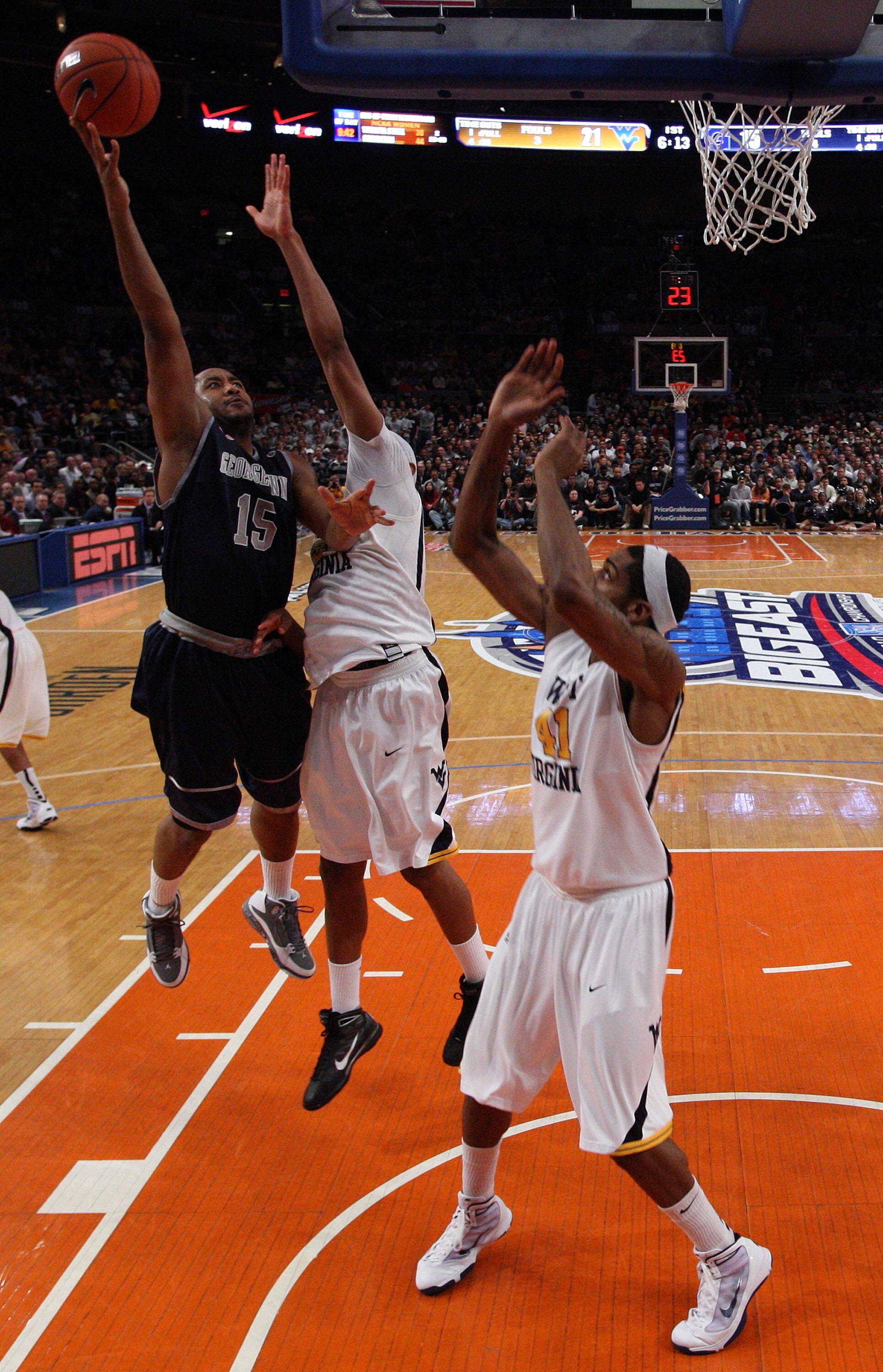 NEW YORK - MARCH 13: Austin Freeman #15 of the Georgetown Hoyas drives to the hoop against Kevin Jones #5 and John Flowers #41 of the West Virginia Mountaineers during the championship of the 2010 NCAA Big East Tournament at Madison Square Garden on March
