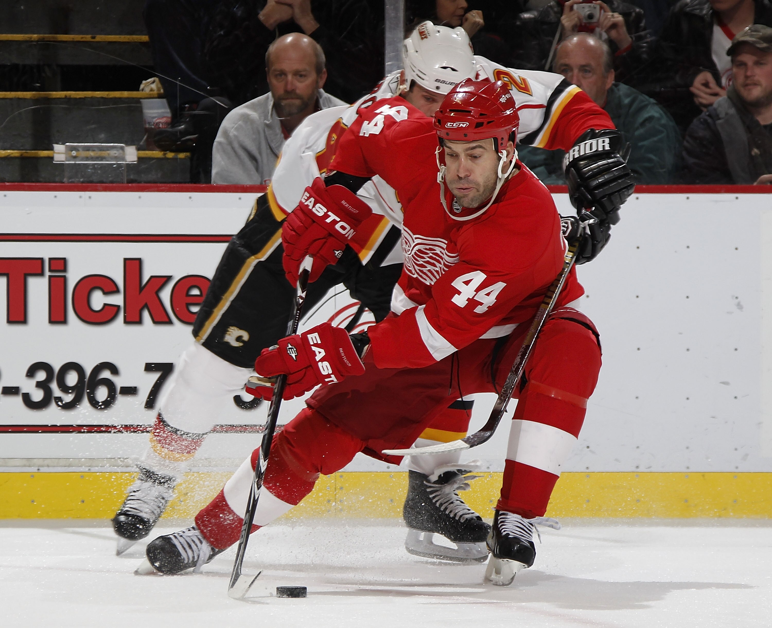 DETROIT - OCTOBER 21: Todd Bertuzzi #44 of the Detroit Red Wings tries to control the puck in front of Craig Conroy #24 of the Calgary Flames on October 21, 2010 at Joe Louis Arena in Detroit, Michigan.  (Photo by Gregory Shamus/Getty Images)
