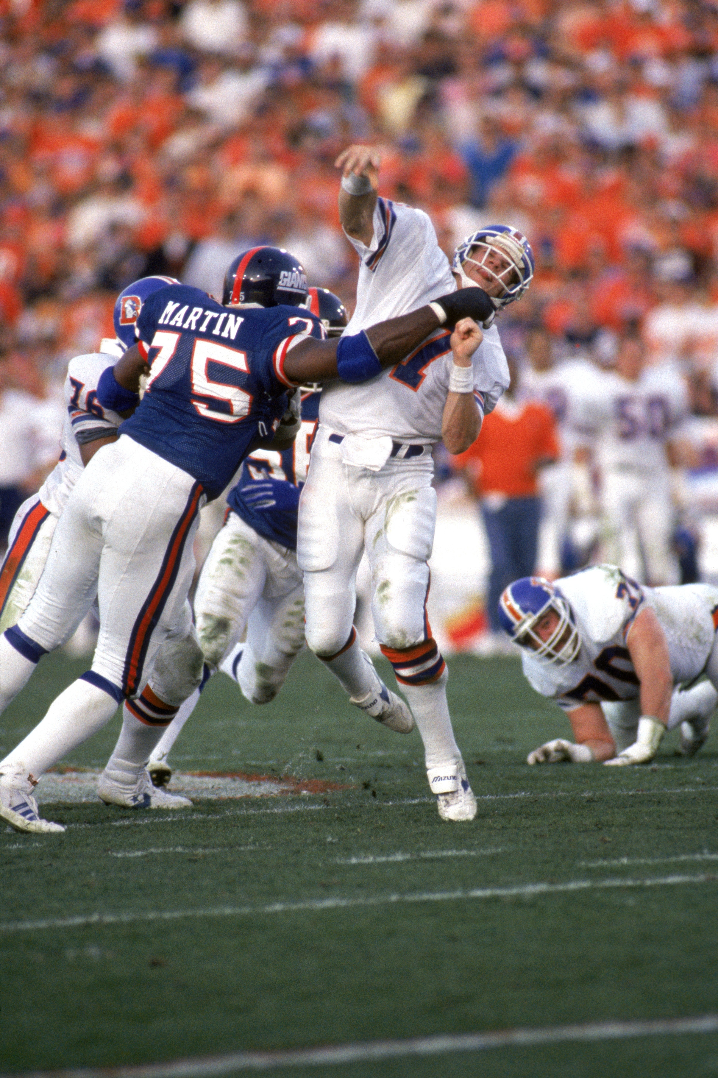 PASADENA, CA - JANUARY 25:  Quarterback John Elway #7 of the Denver Broncos gets rid of the ball just before getting hit by defensive end George Martin #75 of the New York Giants during Super Bowl XXI at the Rose Bowl on January 25, 1987 in Pasadena, Cali