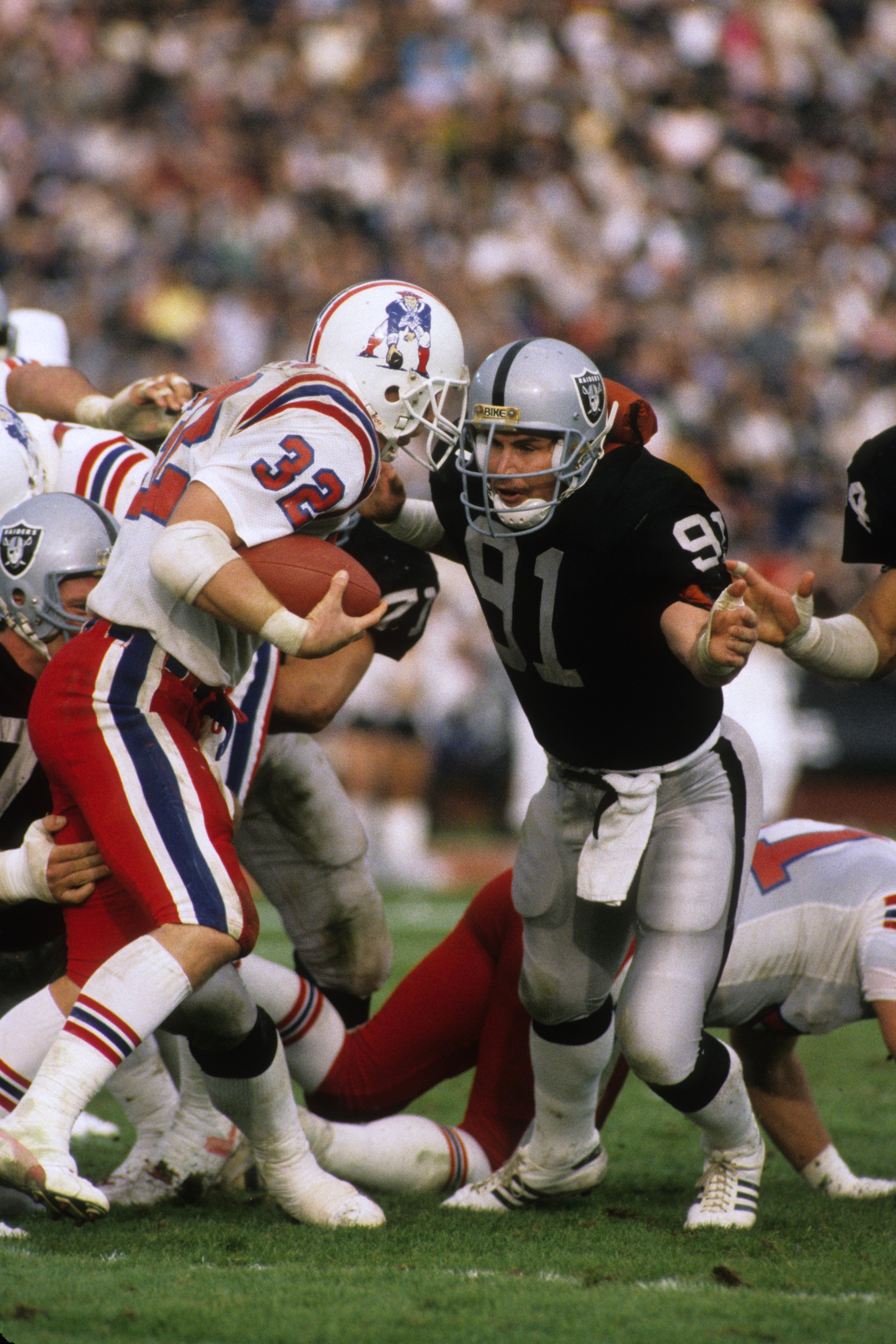 LOS ANGELES - JANUARY 5:  Linebacker Brad Van Pelt #91 of the Los Angeles Raiders closes in for a tackle on running back Craig James #32 of the New England Patriots during the 1985 AFC Divisional Playoff game at the Los Angeles Memorial Coliseum on Januar
