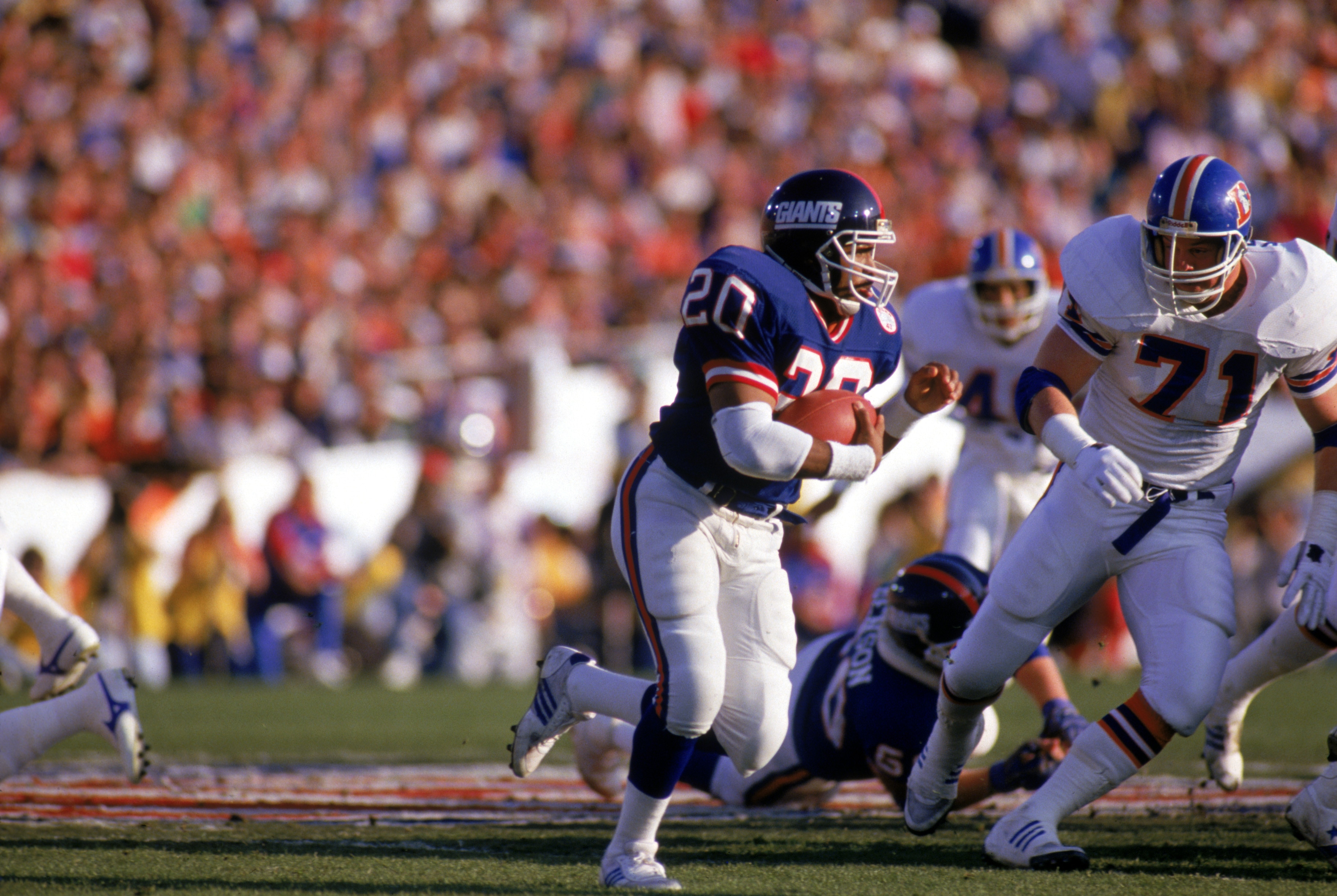 PASADENA, CA - JANUARY 25:  Running back Joe Morris #20 of the New York Giants carries the ball against nose tackle Greg Kragen #71 of the Denver Broncos during Super Bowl XXI at the Rose Bowl on January 25, 1987 in Pasadena, California. The Giants defeat
