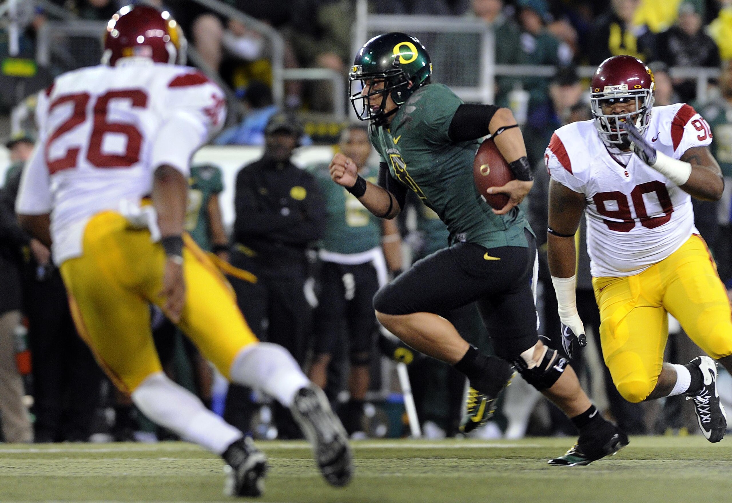 EUGENE, OR - OCTOBER 31: Quarterback Jeremiah Masoli #8 of the Oregon Ducks tucks the ball and heads upfield as safety Will Harris #26 and defensive tackle Derek Simmons #90 of the USC Trojans give chase in the second quarter of the game at Autzen Stadium