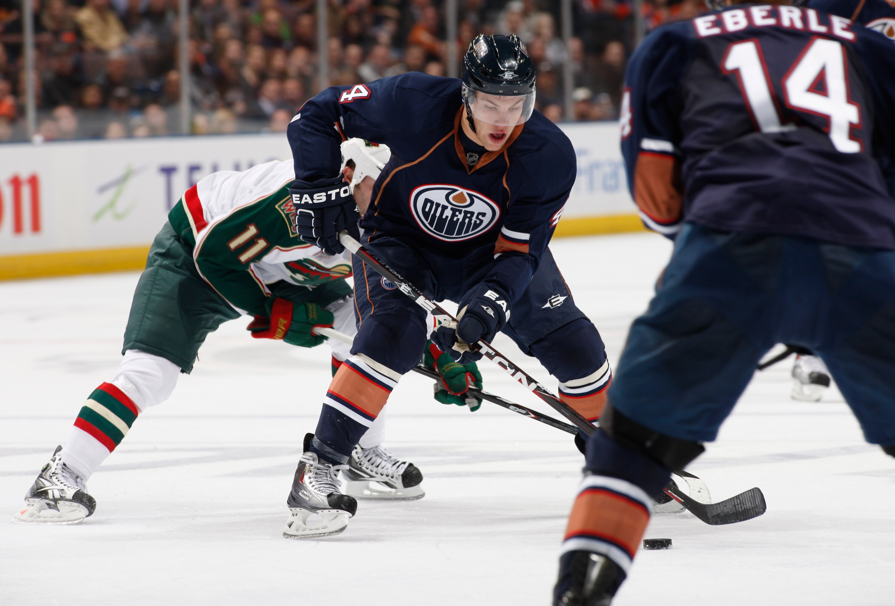 EDMONTON, CANADA - OCTOBER 21:  Taylor Hall #4 of the Edmonton Oilers is checked by John Madden #11 of the Minnesota Wild in second-period action at Rexall Place October 21, 2010 in Edmonton, Alberta, Canada. (Photo by Dale MacMillan/Getty Images)