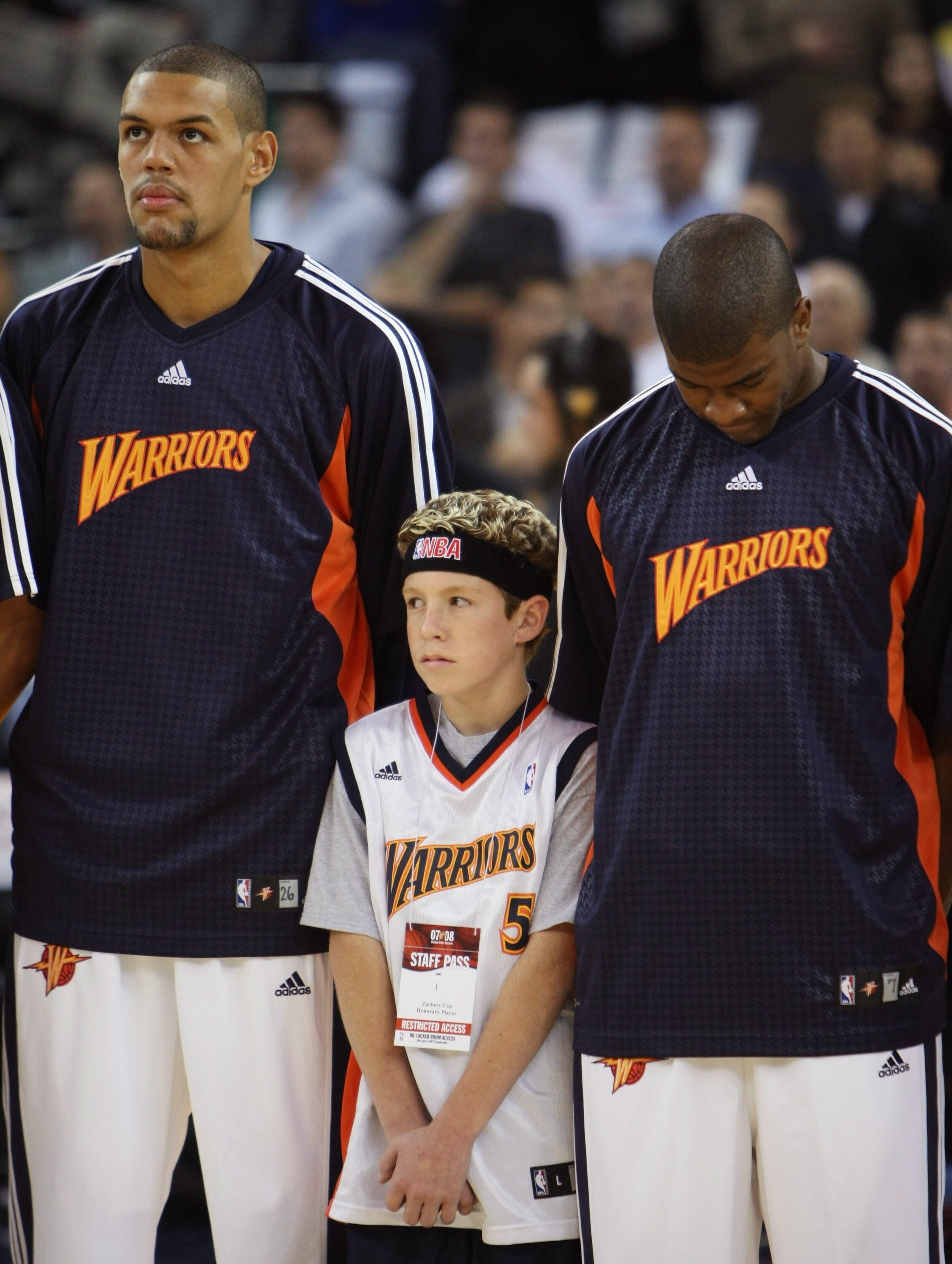 OAKLAND, CA - OCTOBER 30:  Patrick O'Bryant #26, fan Zachery Cox and Kelenna Azubuike #7 of the Golden State Warriors listen to the National Anthem before their game against the Utah Jazz on October 30, 2007 at Oracle Arena in Oakland, California. NOTE TO