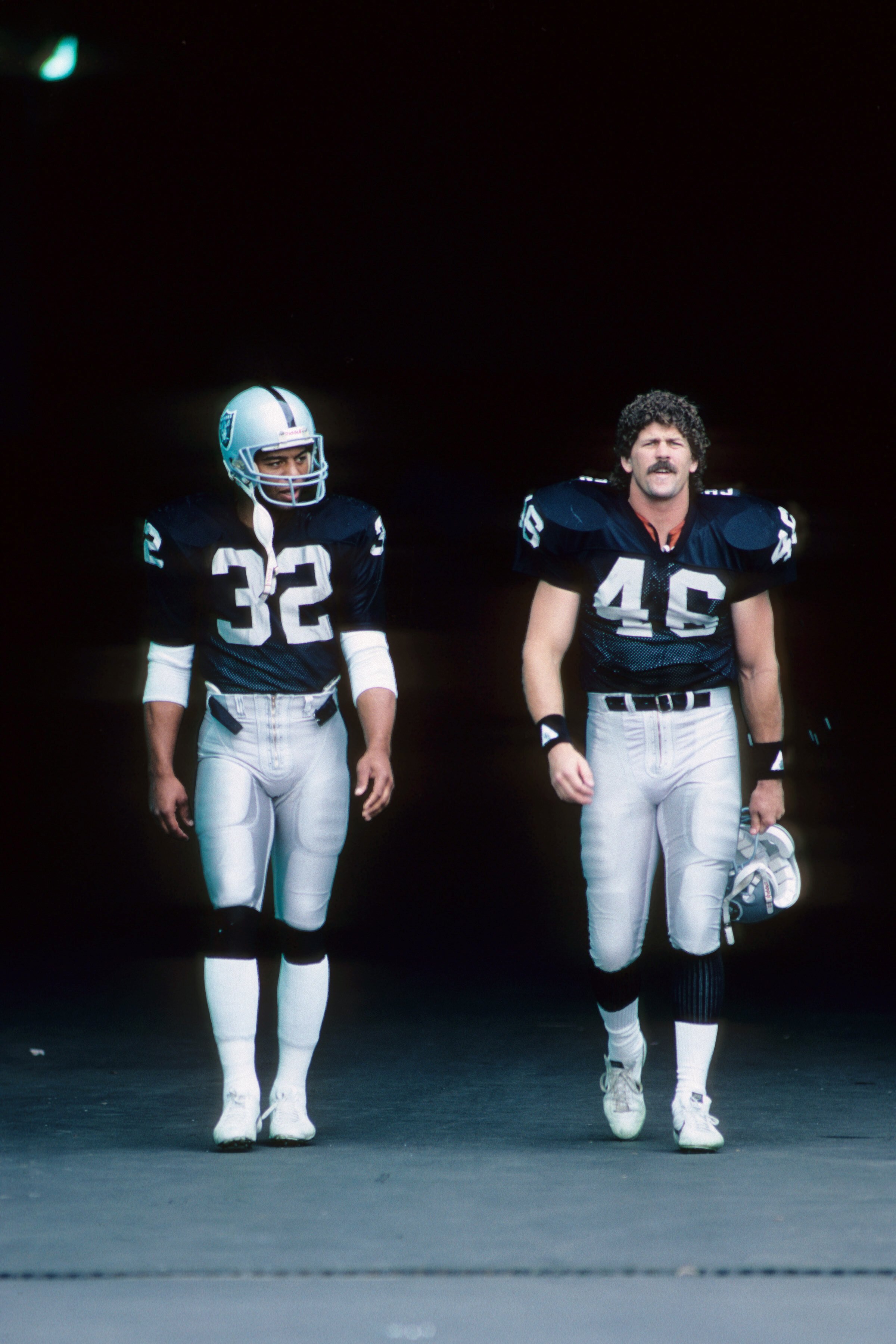 LOS ANGELES, CA - OCTOBER 25:  Marcus Allen #32 and Todd Christensen #46 of the Los Angeles Raiders walk out of the tunnel during the game against the Seattle Seahawks at the Los Angeles Memorial Coliseum on October 25, 1987 in Los Angeles, California.  T