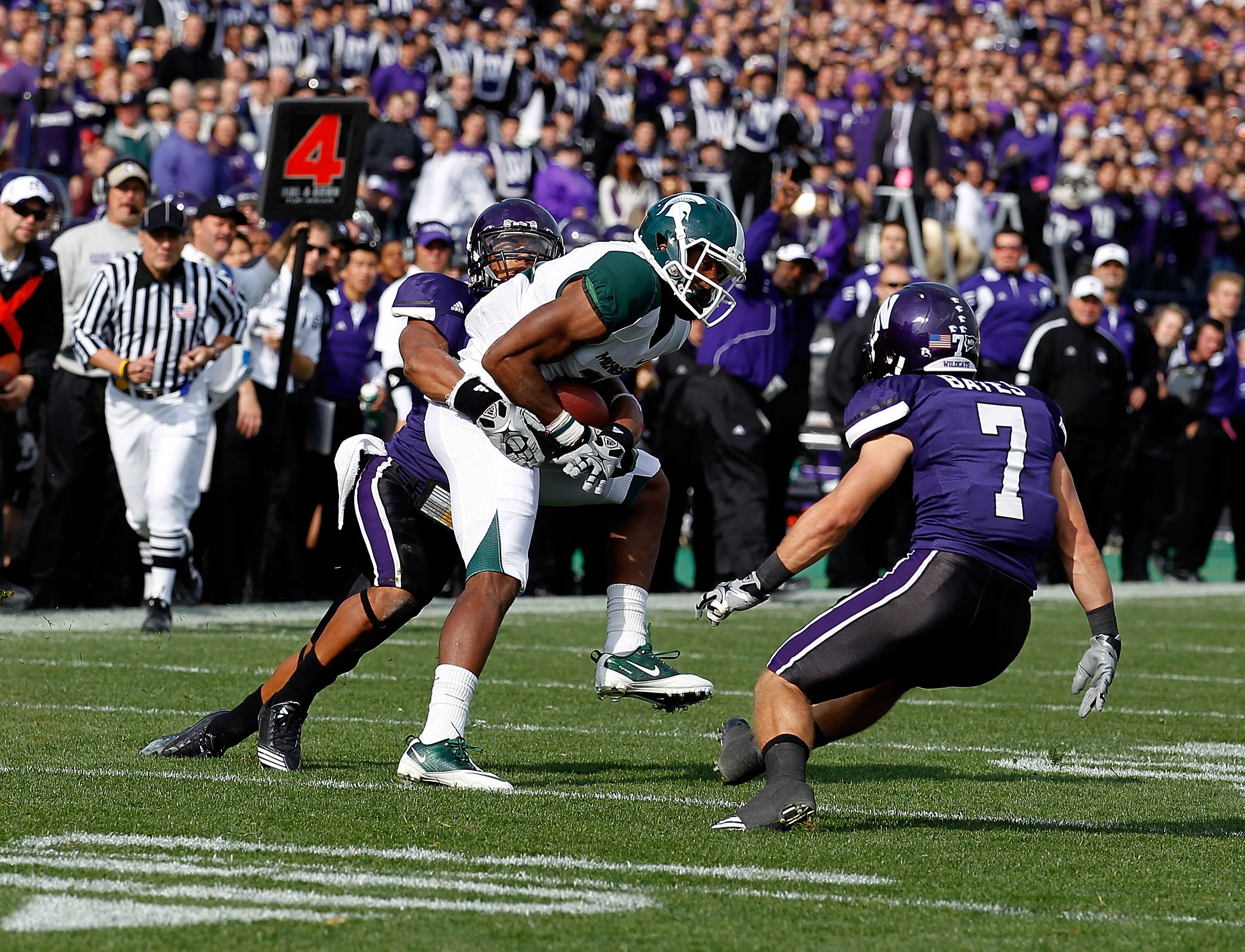 EVANSTON, IL - OCTOBER 23: Bennie Fowler #13 of the Michigan State Spartans catches a first down pass on a fake punt as Jordan Mabin #26 and Hunter Bates #7 of the Northwestern Wildcats close in for the tackle at Ryan Field on October 23, 2010 in Evanston
