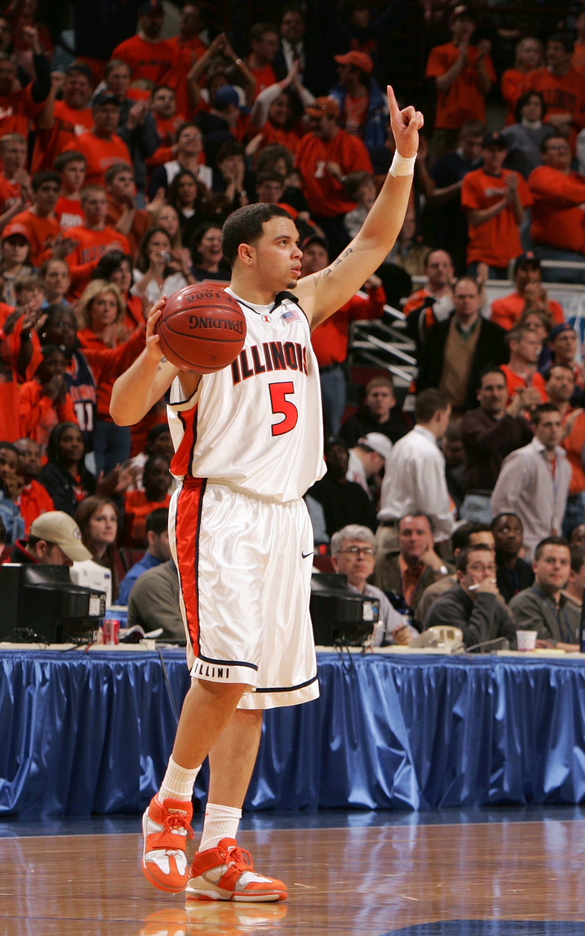 CHICAGO - MARCH 13:  Deron Williams #5 of the Illinois Fighting Illini holds his arm up as he celebrates against a backdrop of orange shirts in the finals seconds against the Wisconsin Badgers during the Final of the Big Ten Men's Conference Basketball To