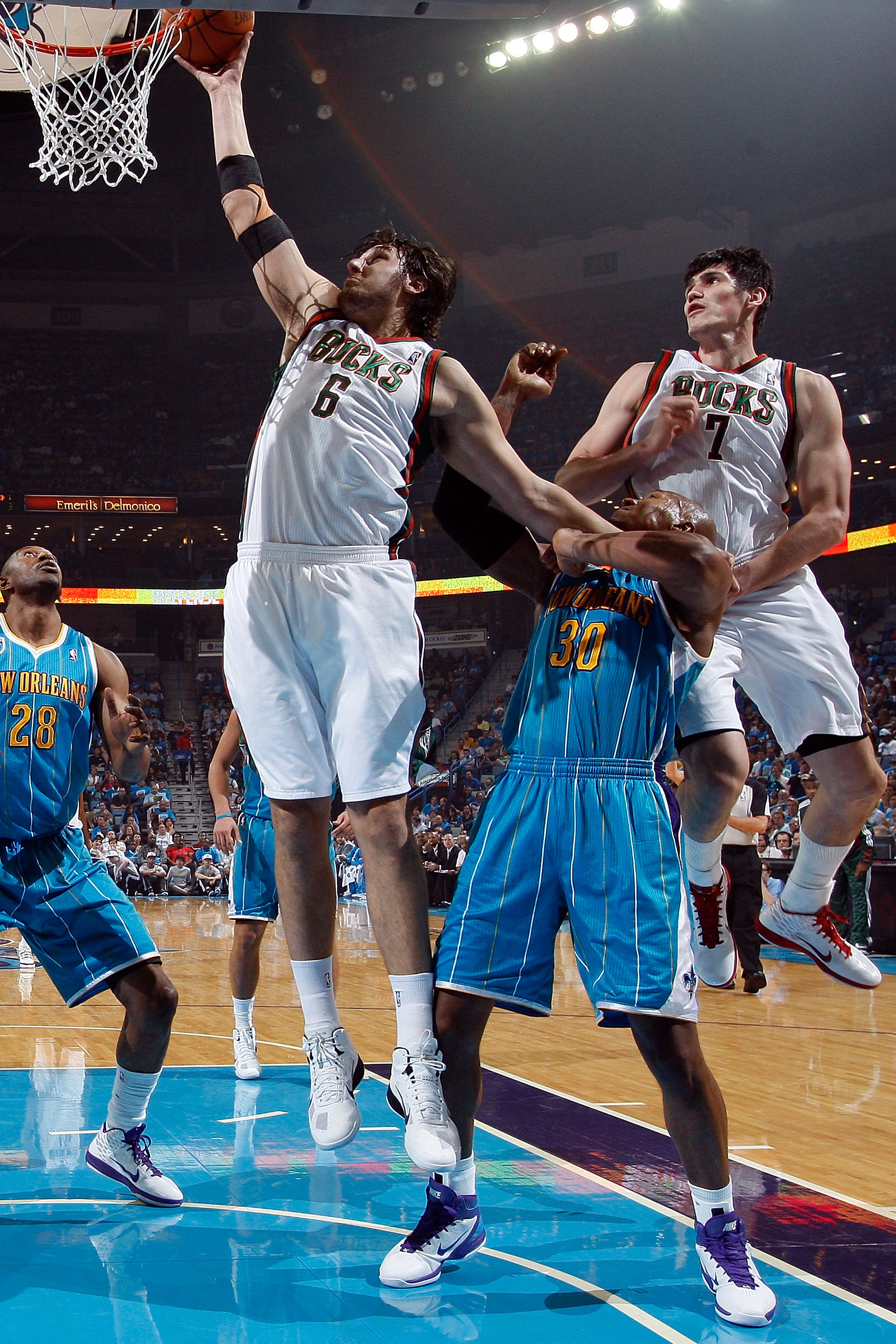 NEW ORLEANS - OCTOBER 27:  Andrew Bogut #6 of the Milwaukee Bucks shoots the ball over Emeka Okafor #50 of the New Orleans Hornets at the New Orleans Arena on October 27, 2010 in New Orleans, Louisiana.   The Hornets defeated the Bucks 95-91.   NOTE TO US