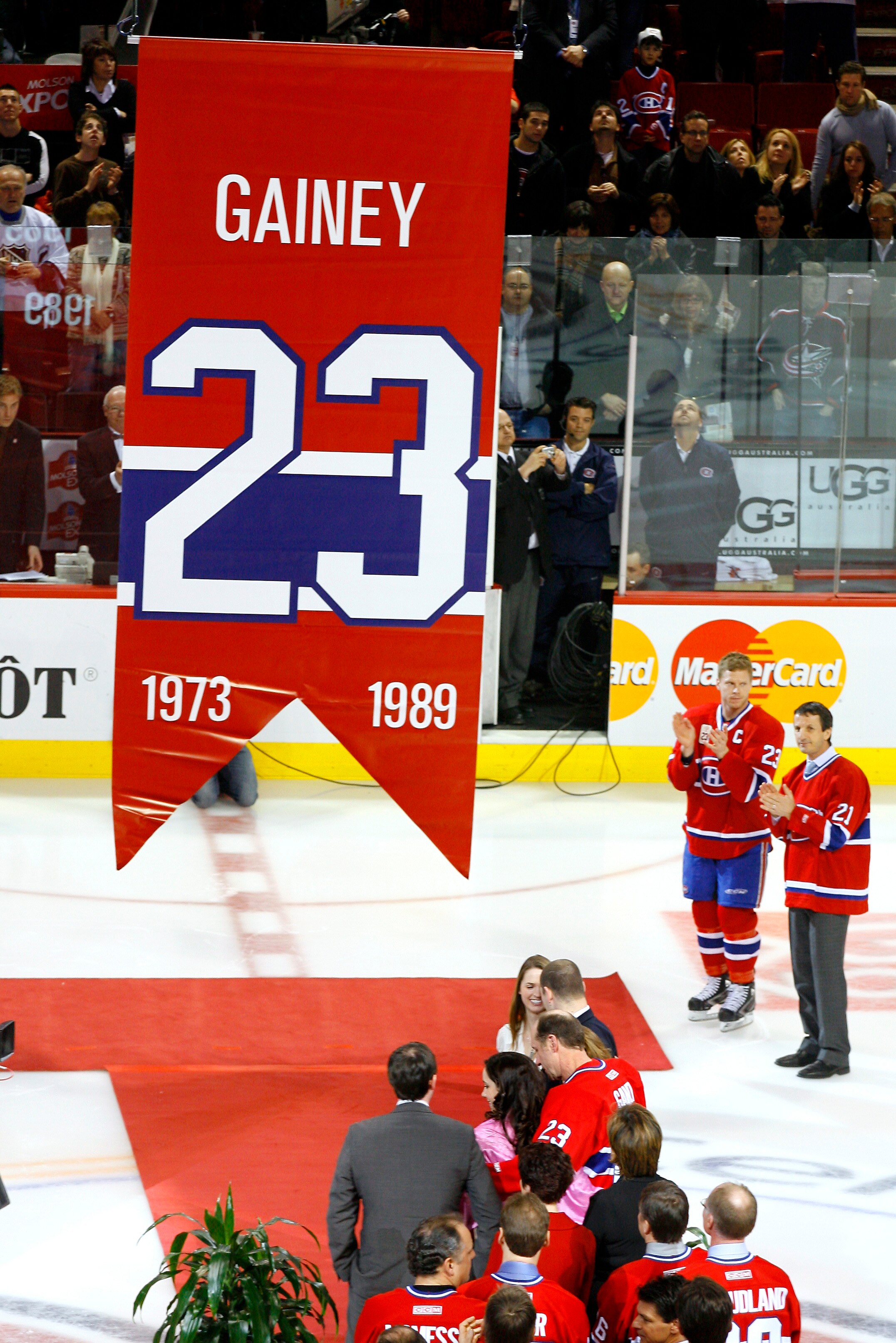 MONTREAL, CANADA - FEBRUARY 23:  Saku Koivu #11 and Guy Carbonneau look on from the side as Bob Gainey, along with his family watches as his jersey number 23 retired by the Montreal Canadiens organization and raised to the rafters before a game on Februar