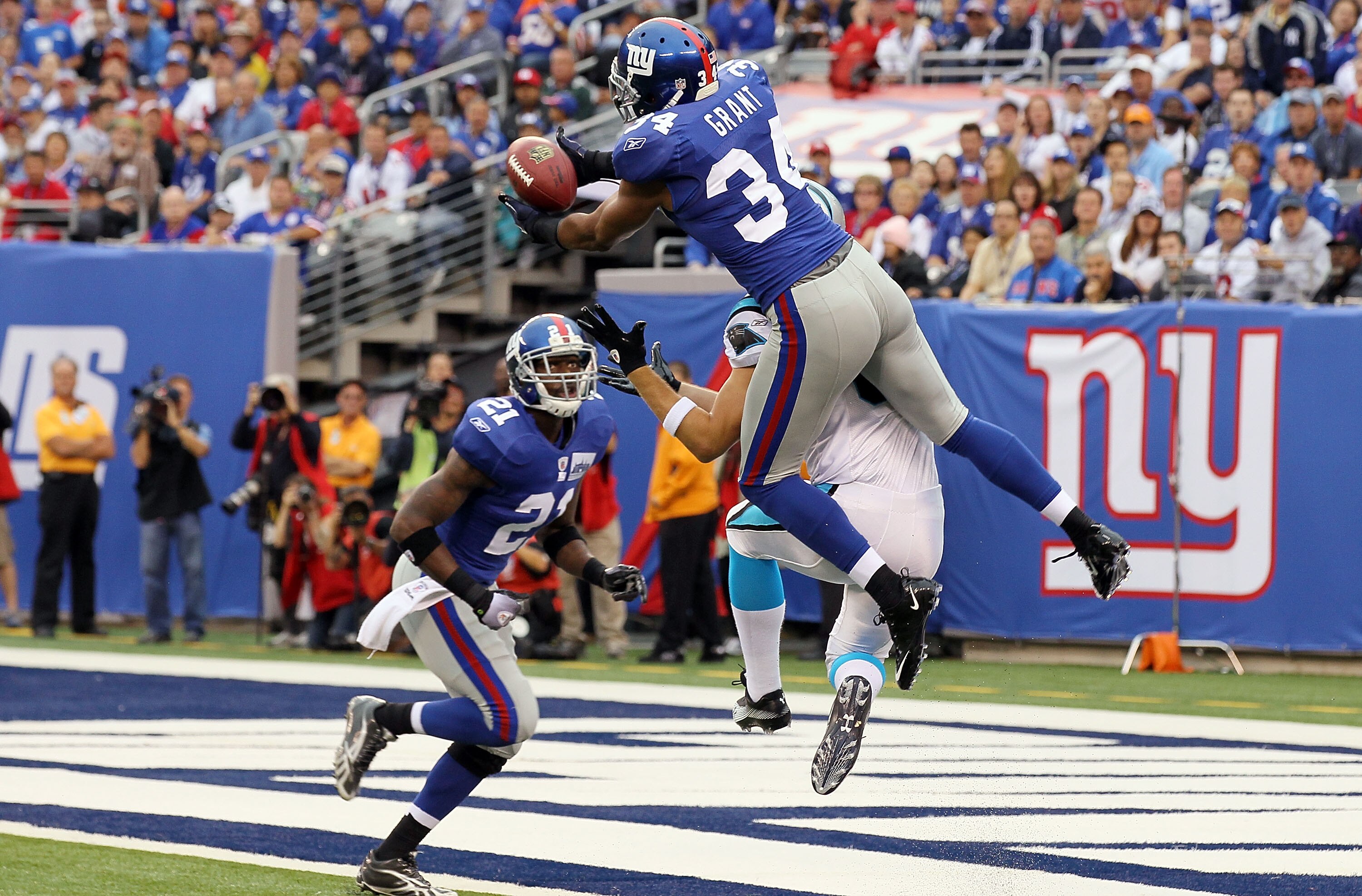 EAST RUTHERFORD, NJ - SEPTEMBER 12:  Deon Grant #34 of the New York Giants intercepts a pass in the endzone intended for Gary Barnidge #82 of the Carolina Panthers as teammate Kenny Phillips #21 defends during the first quarter on September 12, 2010 at th