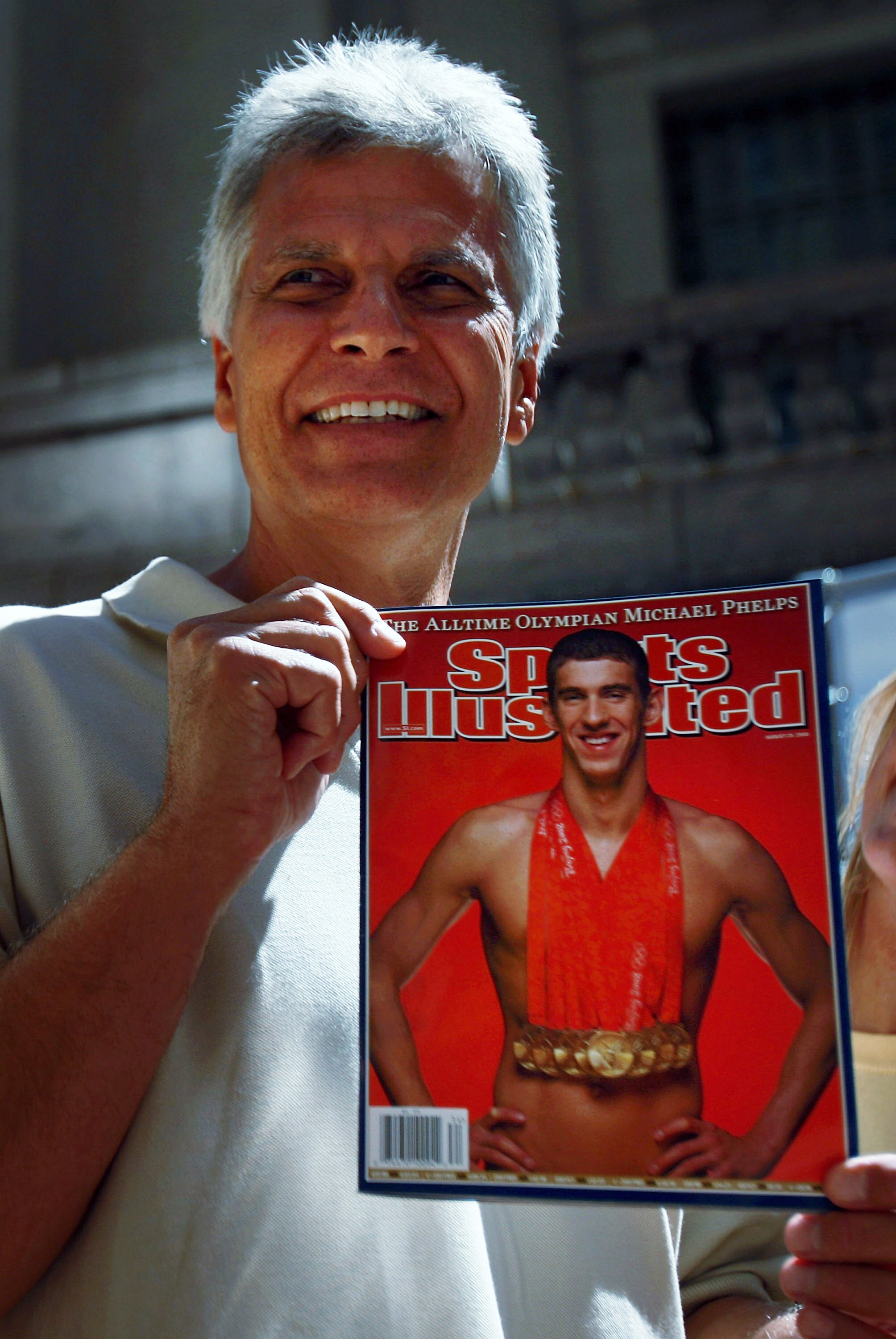 NEW YORK - AUGUST 20:  Swimmer Mark Spitz holds up a copy of the new issue of Sports Illustrated featuring a picture of Olympic swimmer Michael Phelps at Grand Central Station August 20, 2008 in New York City. Spitz's record of breaking seven world record