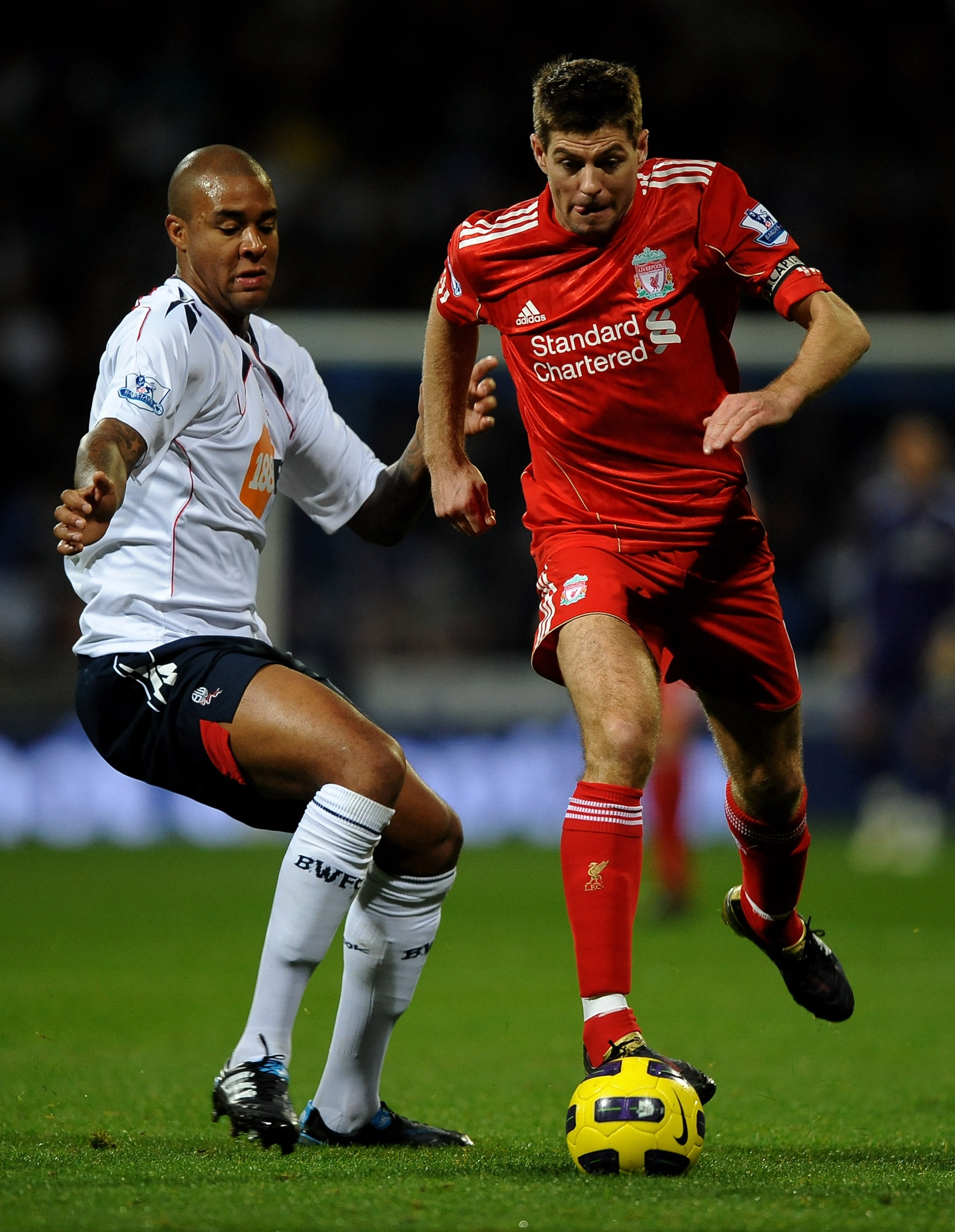 BOLTON, ENGLAND - OCTOBER 31:  Steven Gerrard of Liverpool goes past Zat Knight of Bolton Wanderers during the Barclays Premier League match between Bolton Wanderers and Liverpool at the Reebok Stadium on October 31, 2010 in Bolton, England.  (Photo by La