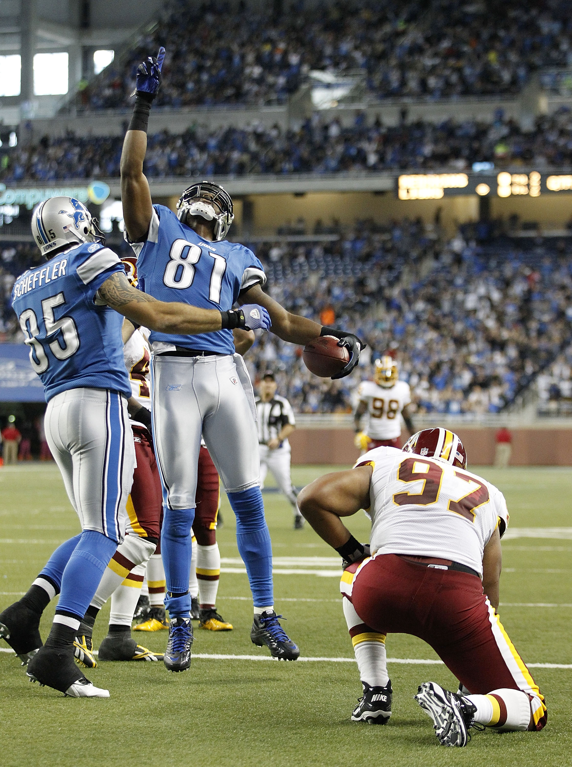 DETROIT - OCTOBER 31:  Calvin Johnson #81 of the Detroit Lions scores a second quarter touchdown as is congratuated by teamate Tony Scheffler #85 as Lorenzo Alexander #97 of the Washington Redskins looks on during the game at Ford Field on October 31, 201